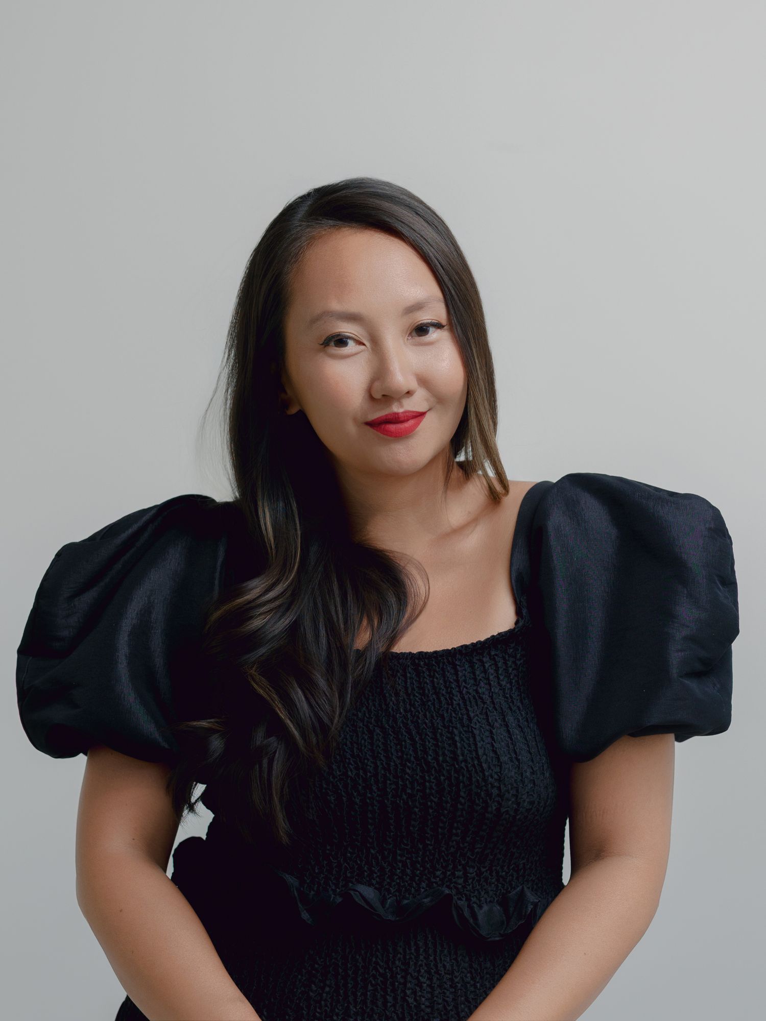 A series of four portrait photos showing someone in a black puff sleeve dress posing against a light gray background.