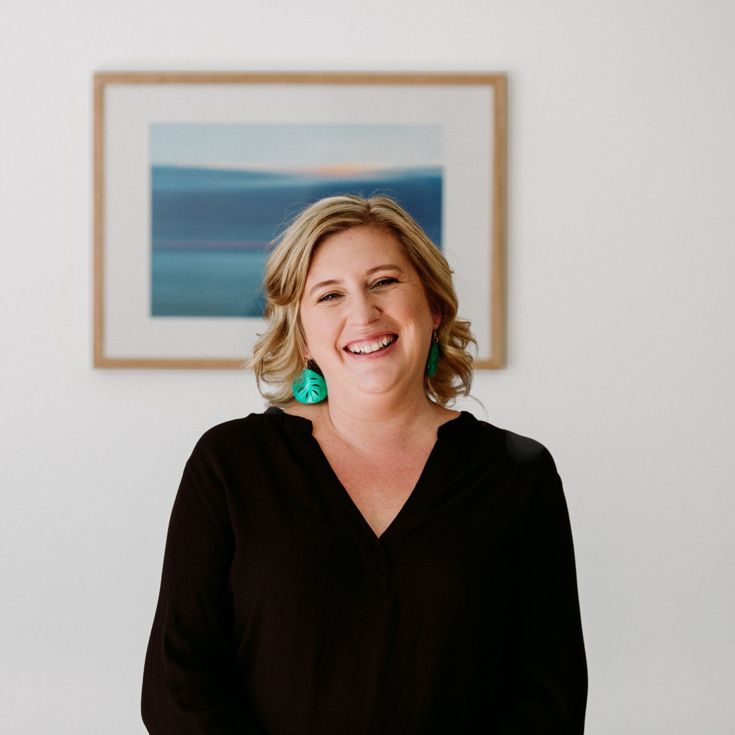 Professional headshot series showing a person in black against white background smiling warmly in studio lighting.