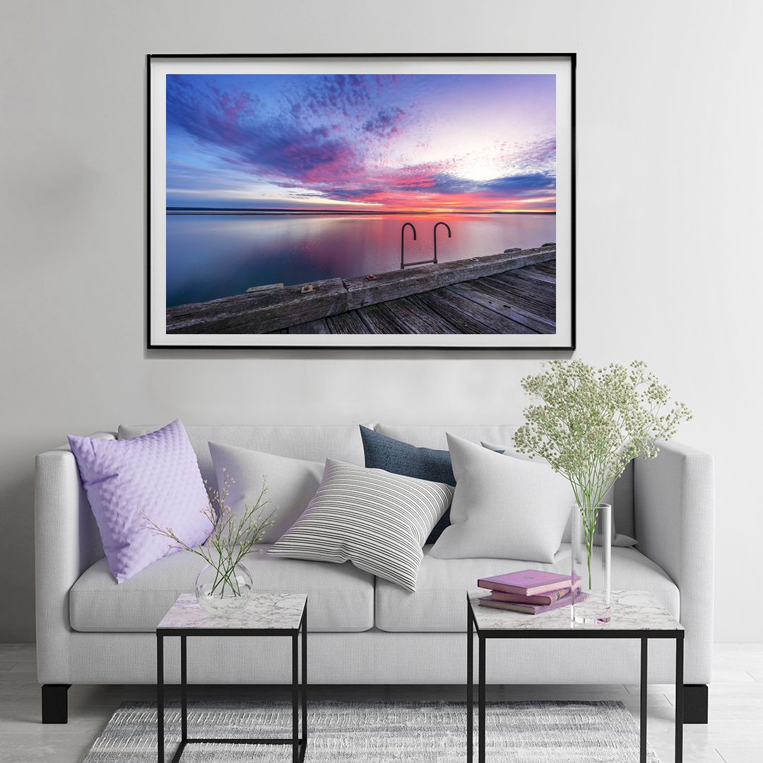 Modern living room interior with framed coastal artwork and minimalist gray furniture against white walls.