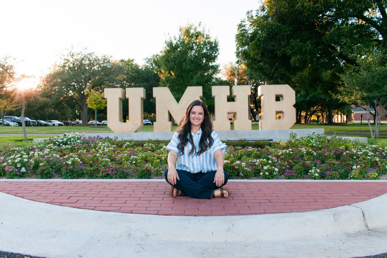 Graduate sitting at UMHB letters in Belton Texas during senior session