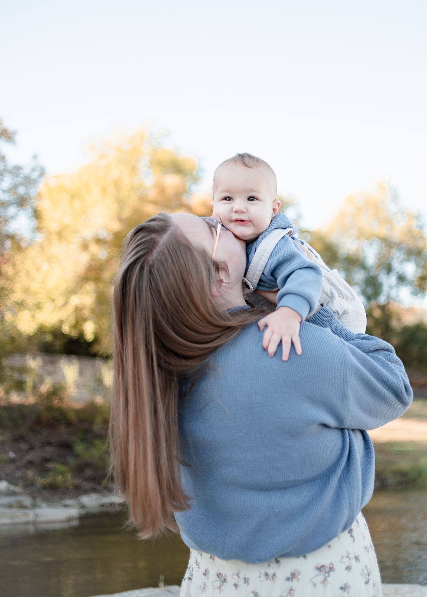 Mother kissing baby during outdoor family session at Nolan Creek in Belton Texas