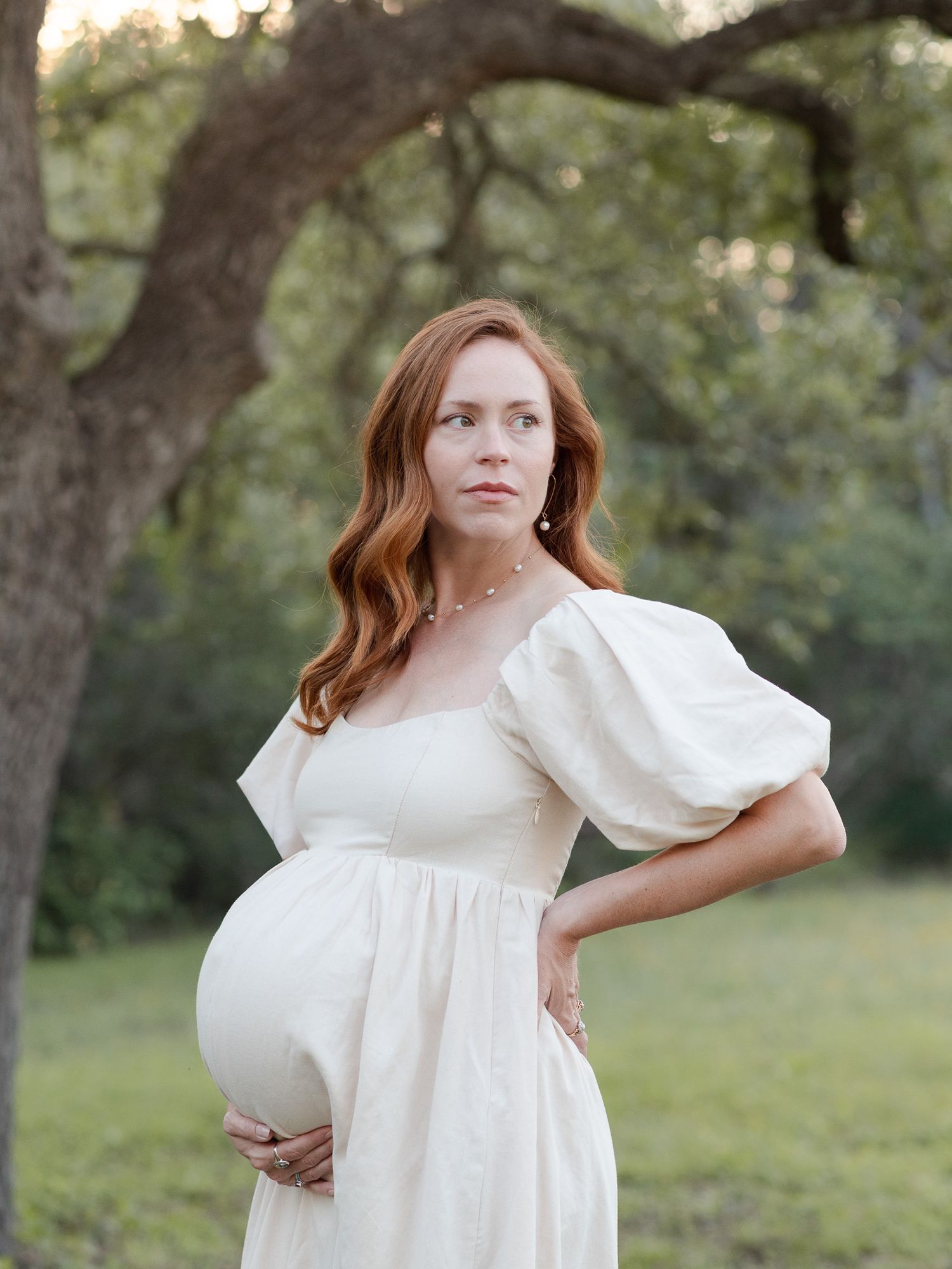 Maternity portrait of expecting mother in flowing dress outdoors in Central Texas with soft natural light