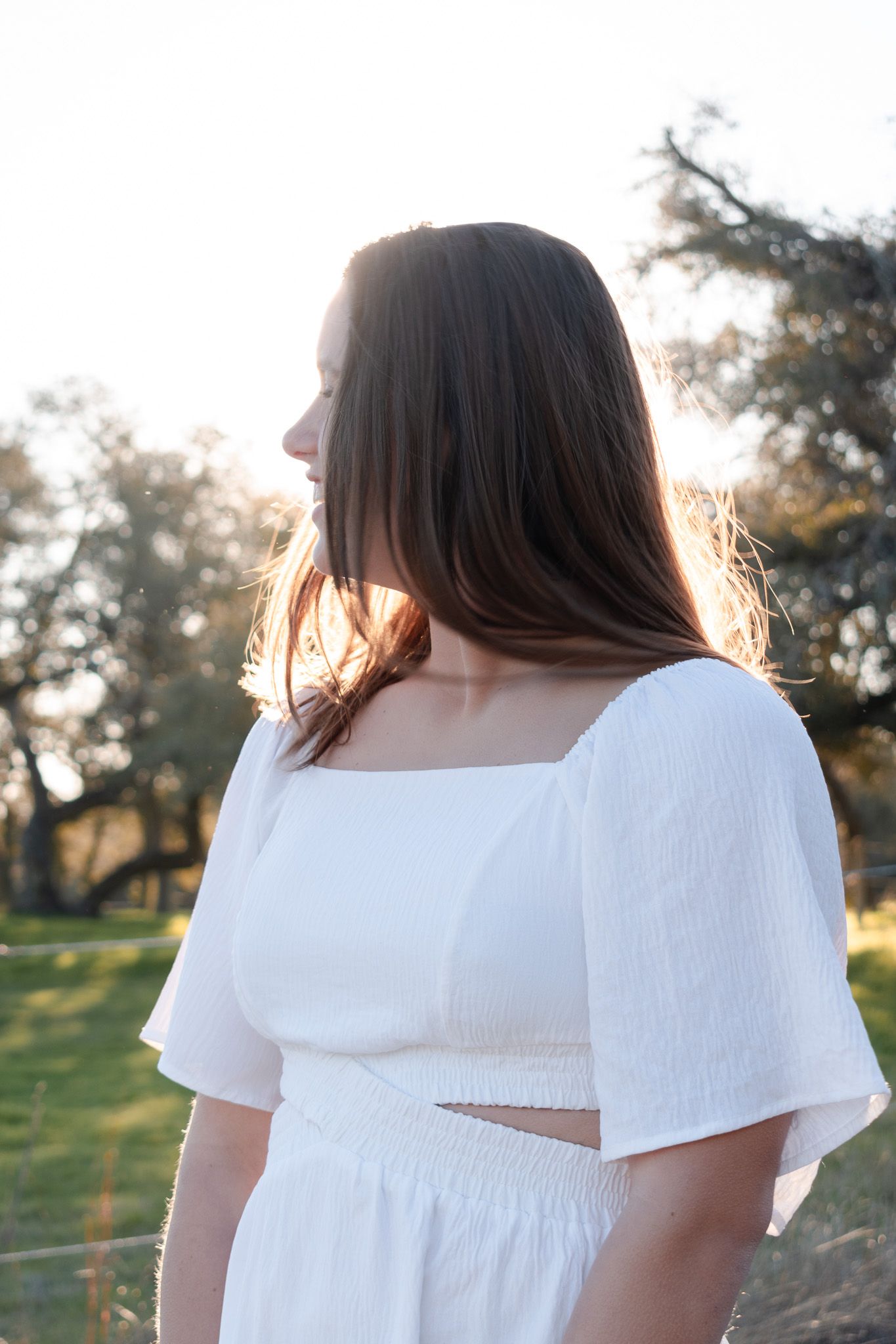 High school senior looking toward sunrise during outdoor session in Central Texas