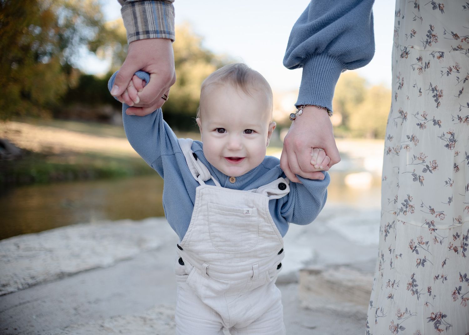 Baby standing with parents during outdoor family session at Nolan Creek in Belton Texas