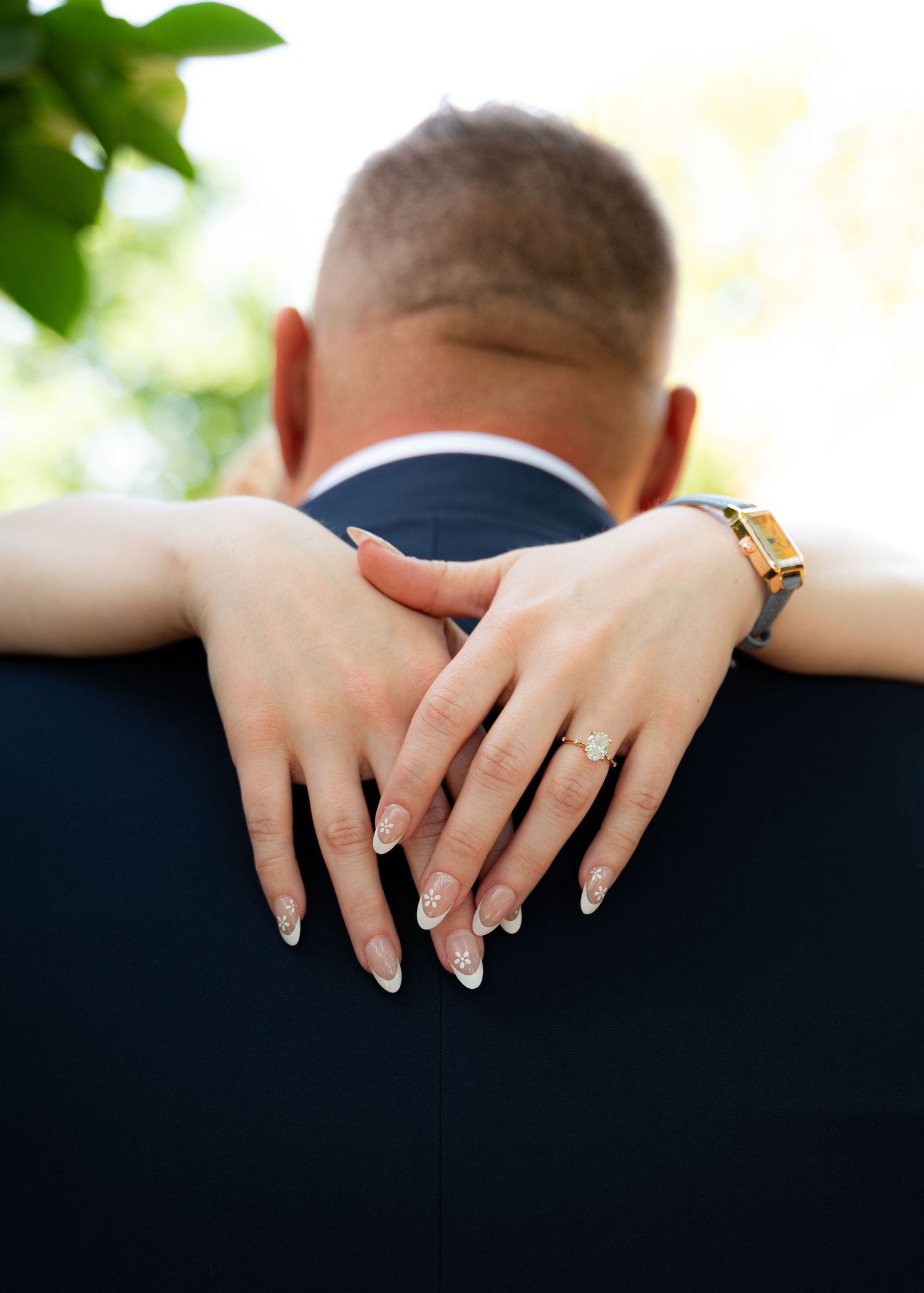 Elegant manicured hands with wedding rings displayed against dark background.