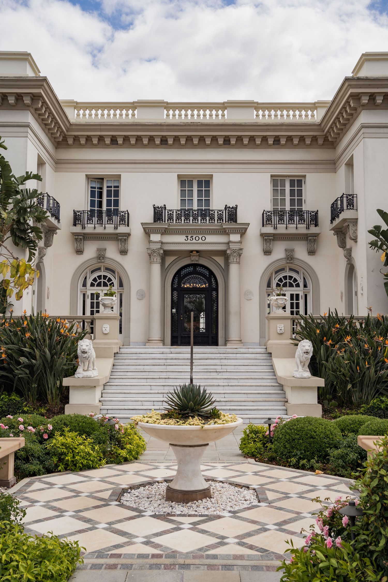 Elegant white mansion with classical architecture featuring symmetrical design and manicured gardens.