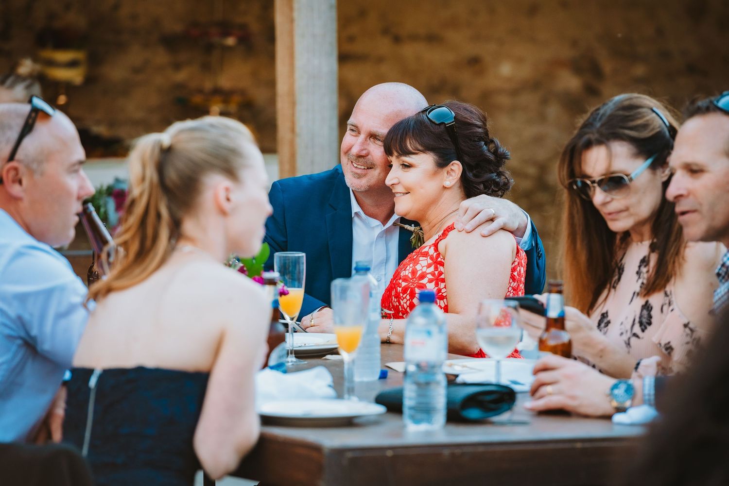 Candid shot of friends enjoying drinks and conversation at an outdoor gathering at sunset.