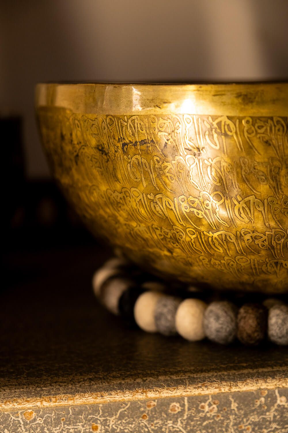 Close-up view of an antique Tibetan singing bowl with intricate engravings and traditional white beads.