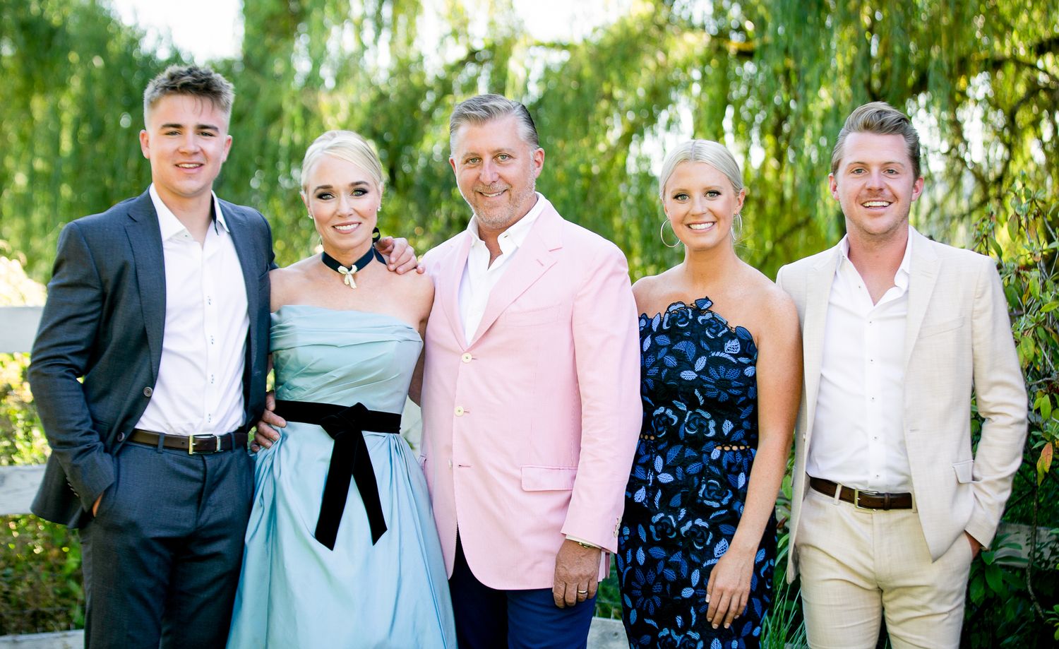 Wedding party and guests pose for casual group photos in outdoor garden venue.