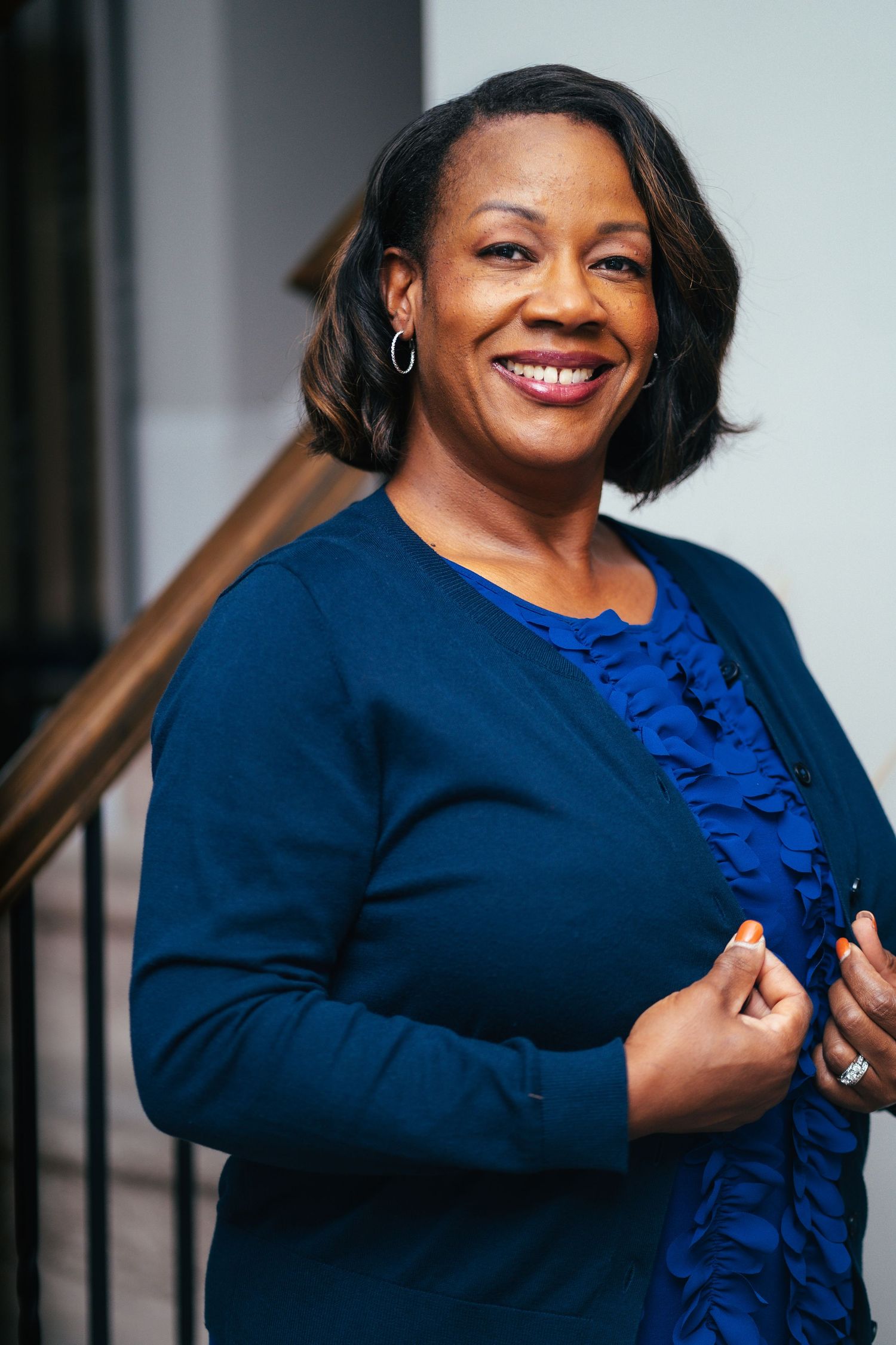 Professional headshot featuring a navy blazer and bright blue accent against a light backdrop.