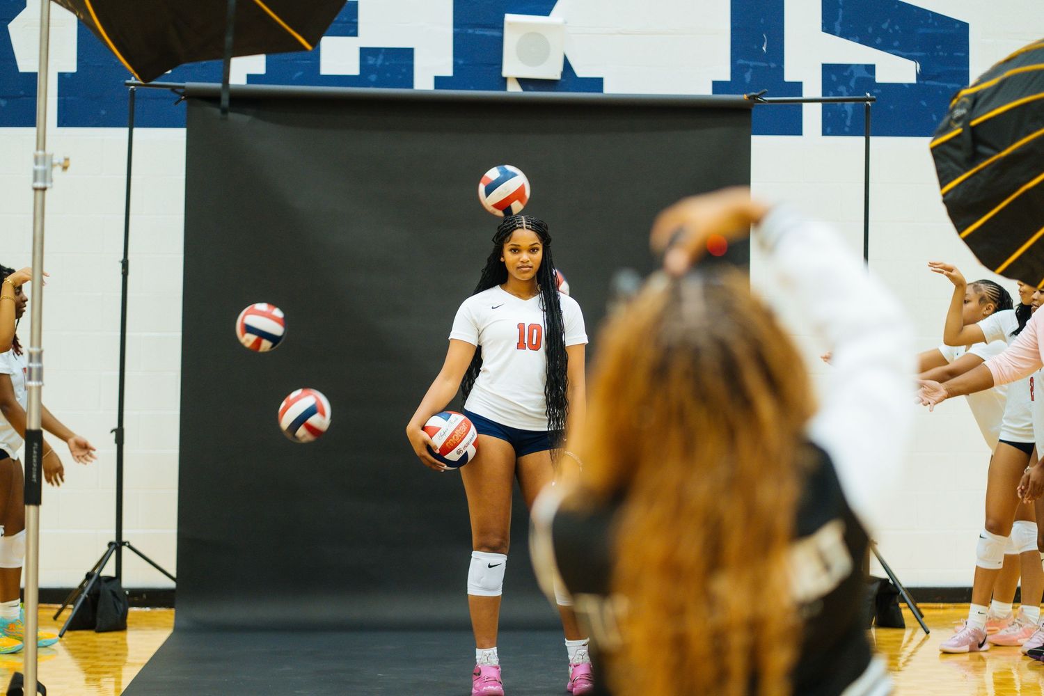 Volleyball player practicing with multiple balls floating in studio setting.
