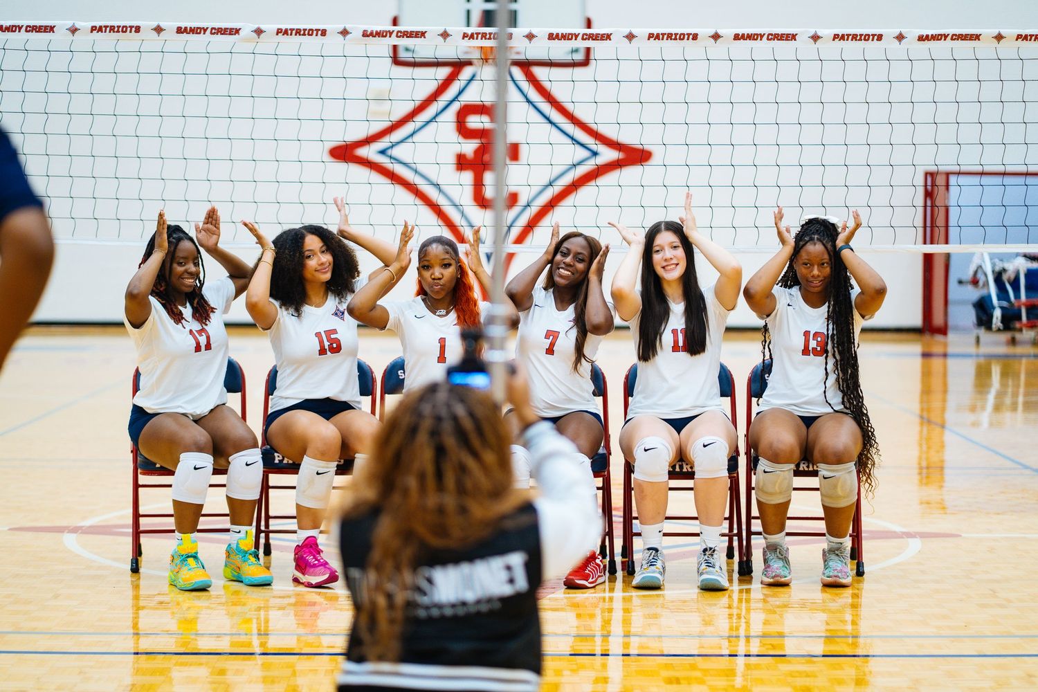Volleyball team members seated for group photo under gym logo.