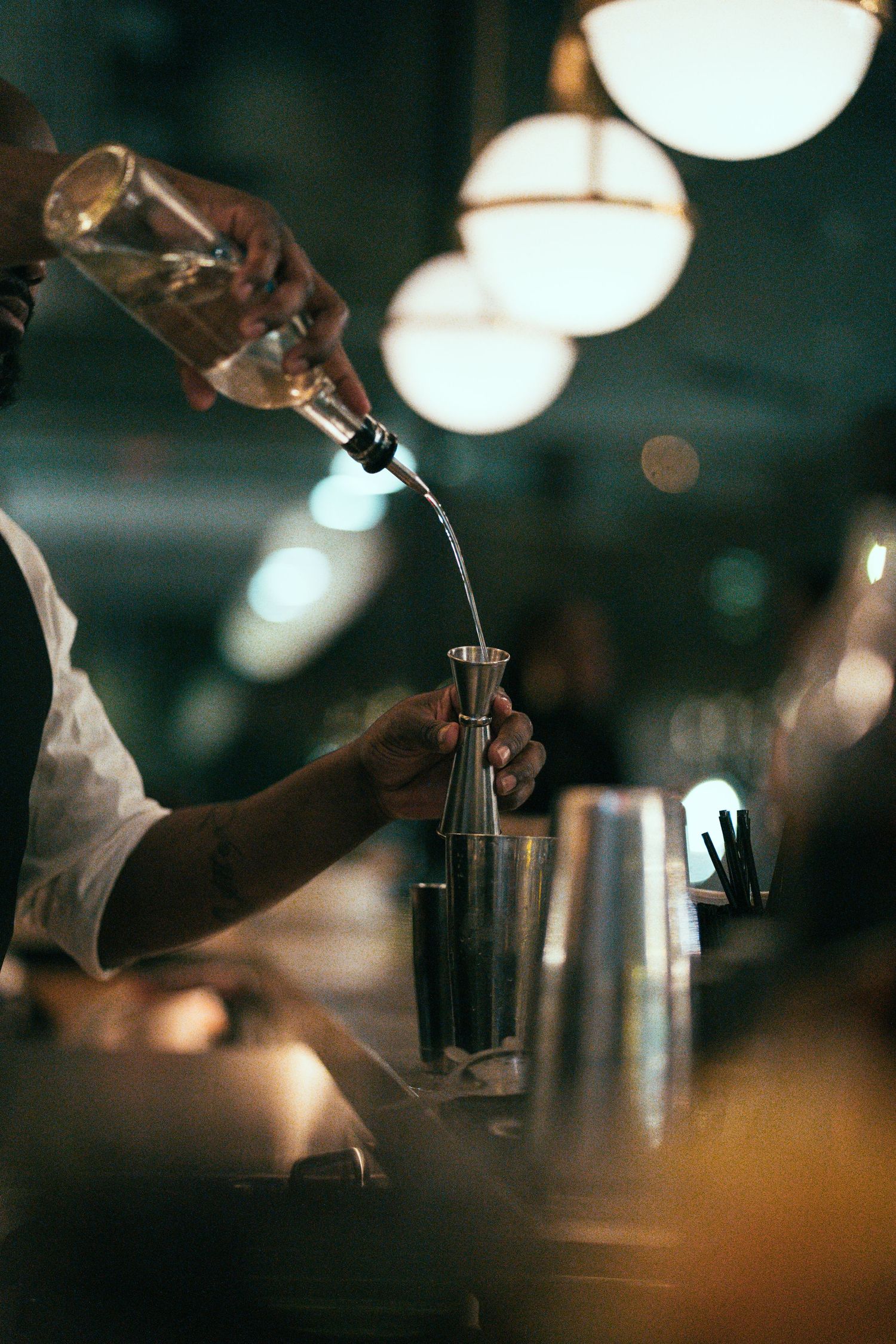 A sequence of blurred bar scenes showing hands pouring drinks in dim lighting with bokeh effects in the background.