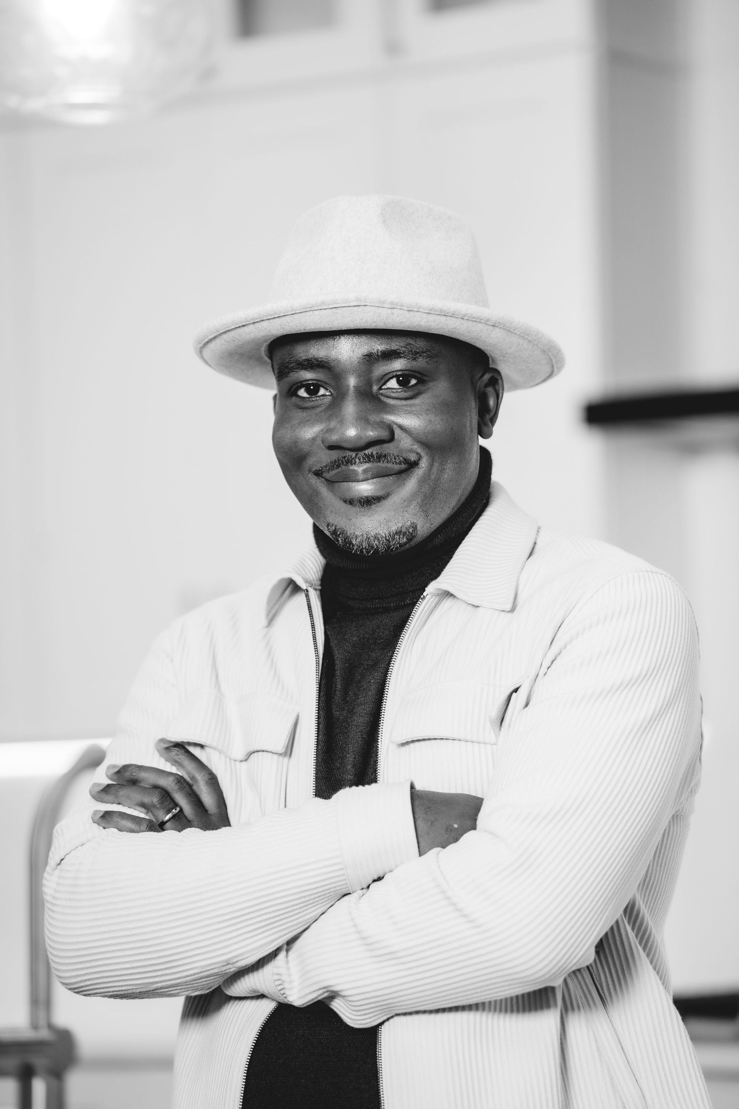 A series of black and white portraits showing someone in a white hat and jacket against a light background.