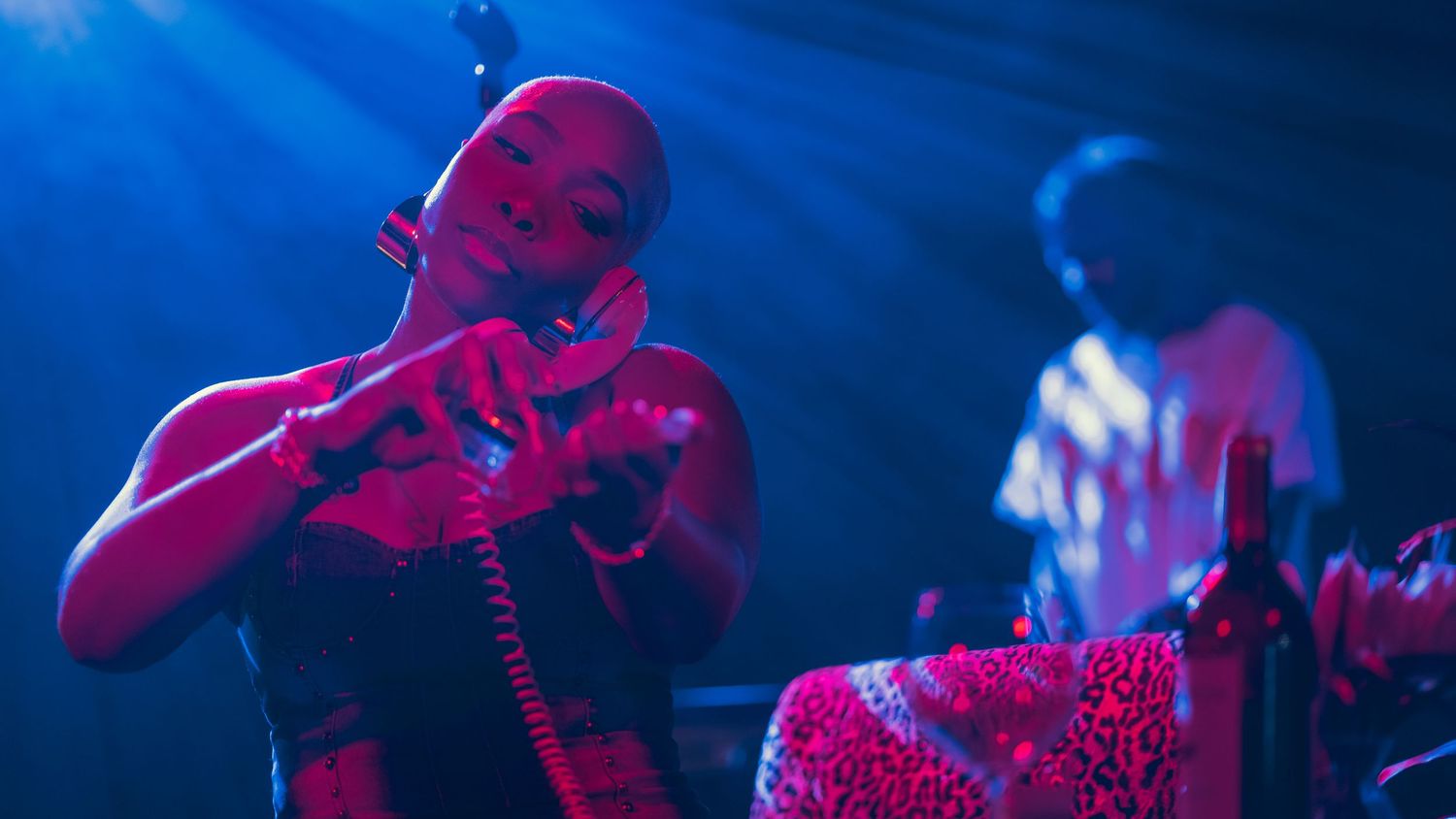 Bald female artist plays violin on stage bathed in dramatic blue spotlight during live performance.