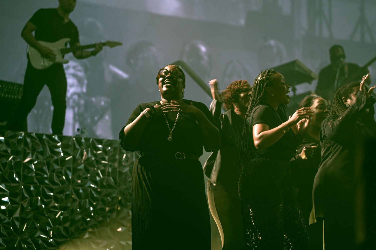 A powerful female vocalist performs on stage with a band during an energetic live gospel music concert.