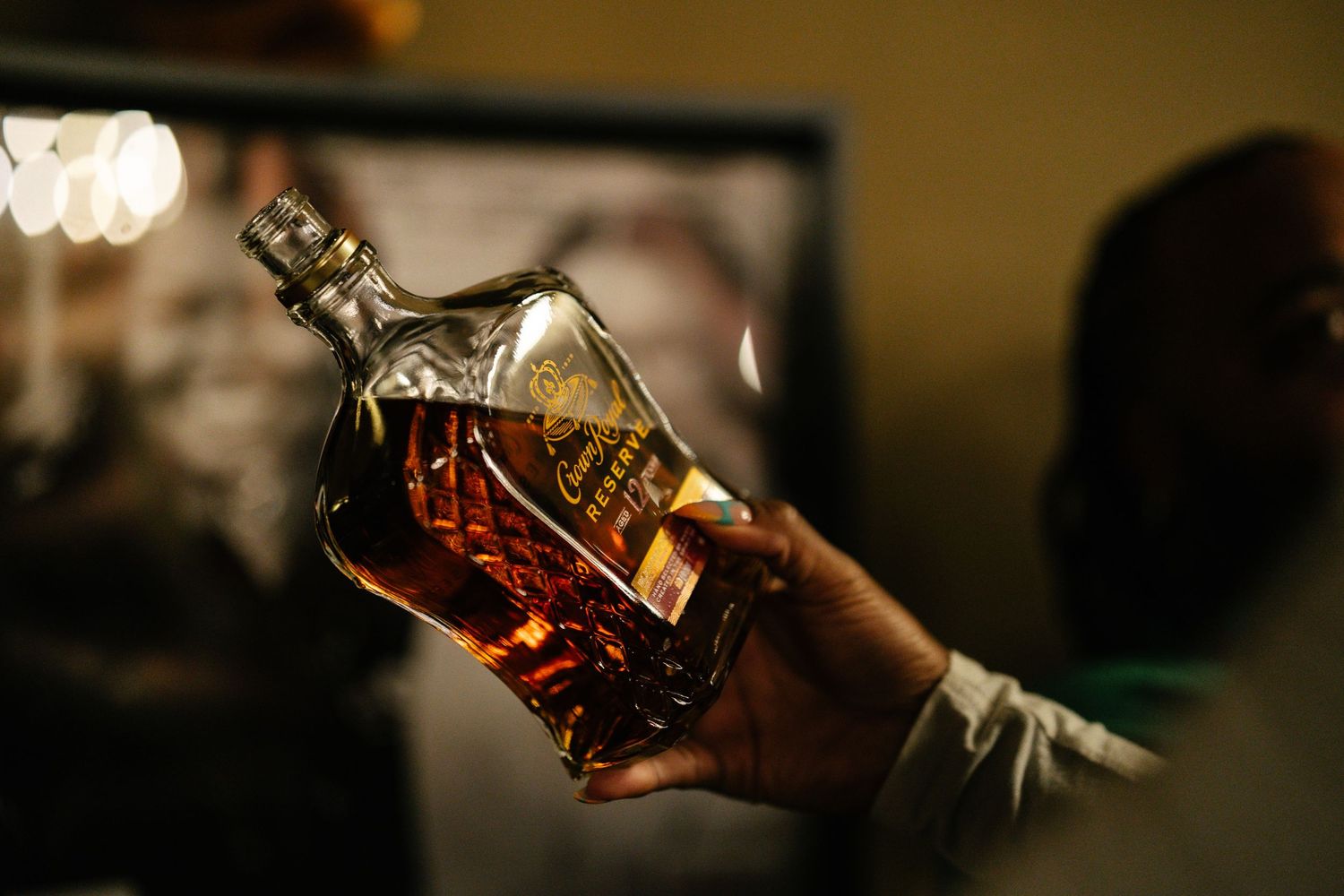 Person holding a large bottle of Johnnie Walker whiskey in a dimly lit room.