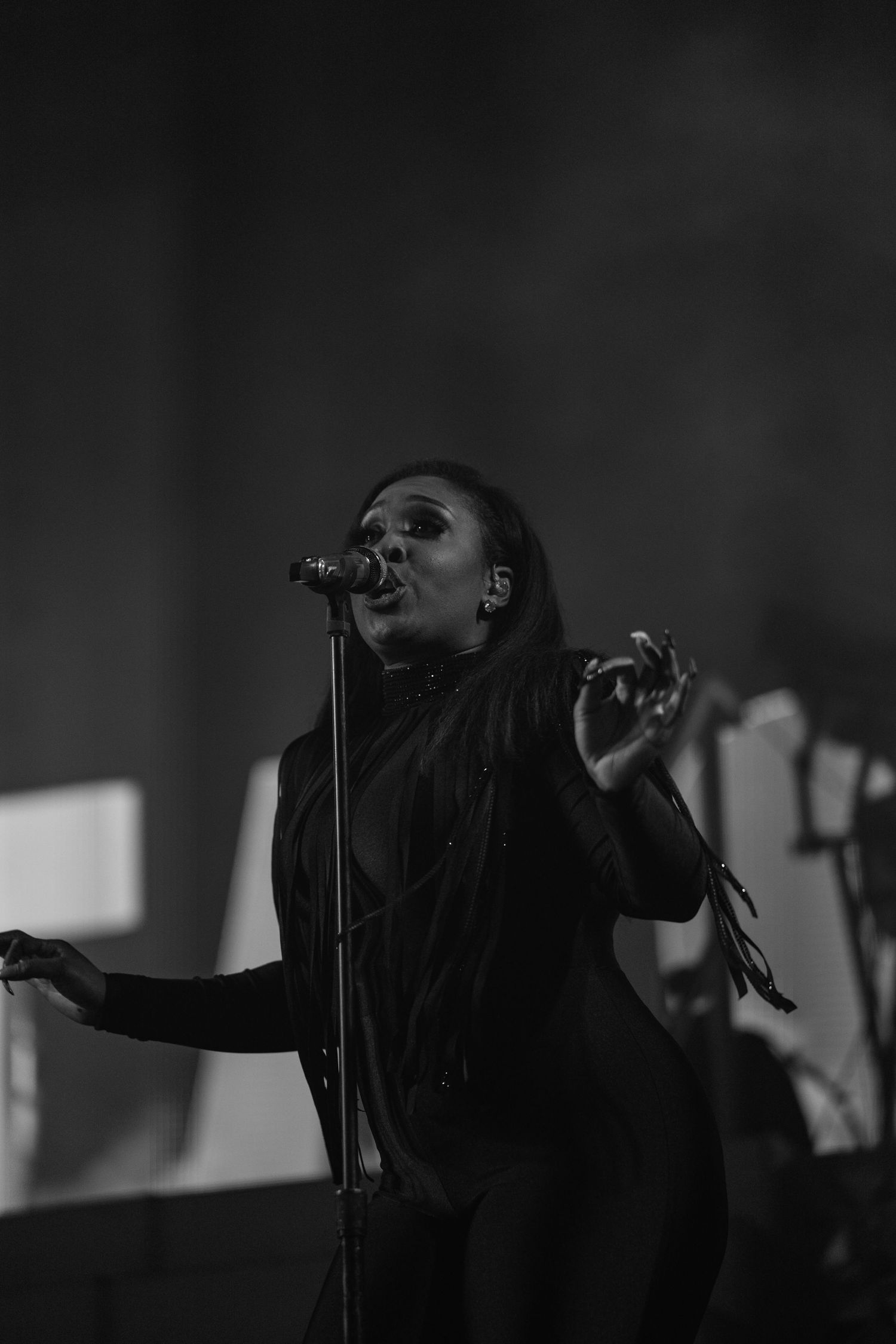 Black and white photo of a female singer performing on stage with a microphone stand.