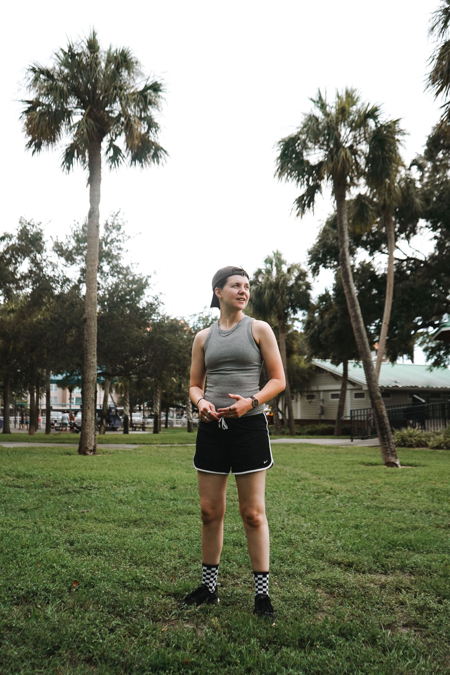 Person exercising outdoors in athletic wear with palm trees in background.