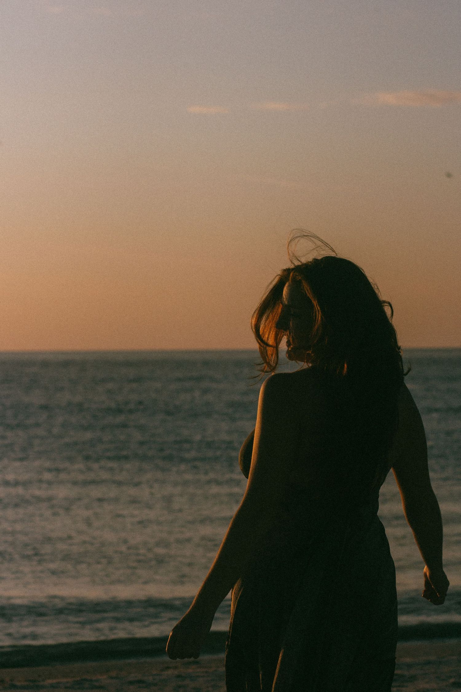 Silhouette of person standing on beach during golden hour.