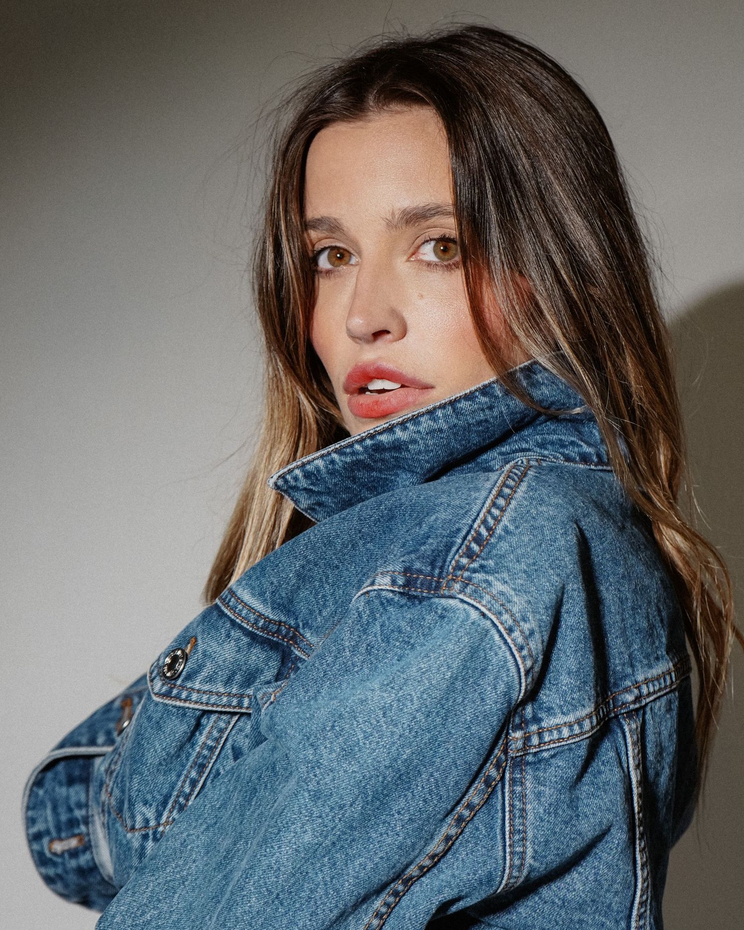 Closeup fashion portrait featuring classic blue denim jacket against grey background.