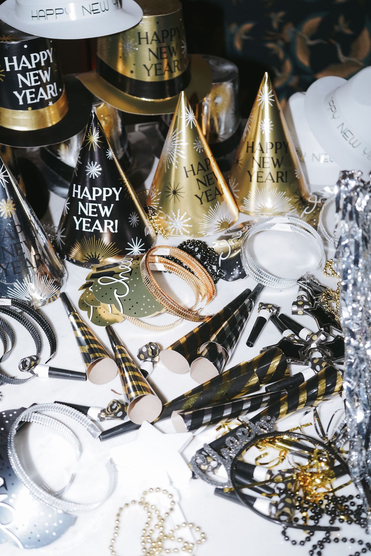 New Year's party decorations including gold party hats, noisemakers, and silver confetti.