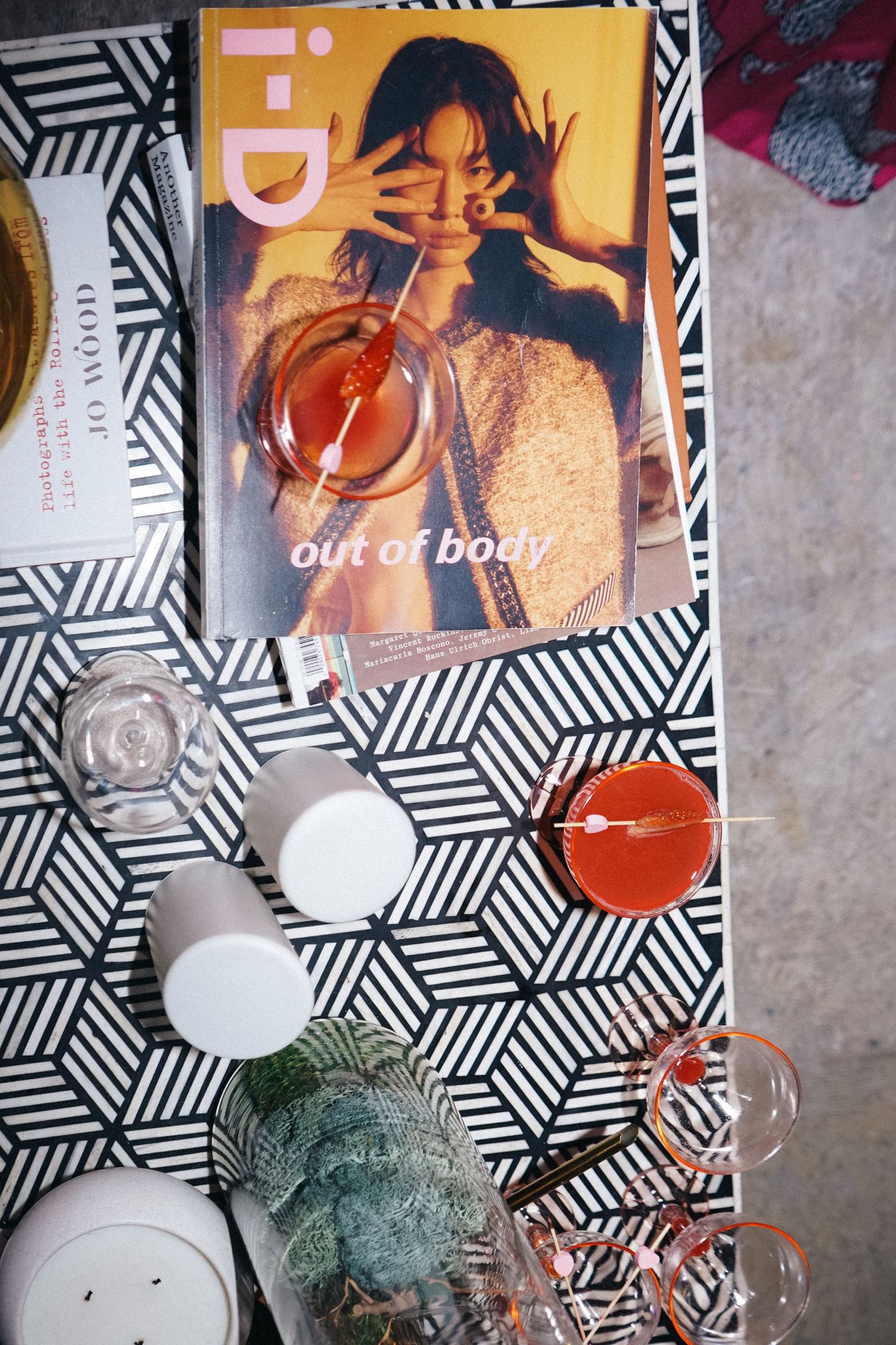 Magazine cover and cocktail glasses arranged on patterned surface with decorative items.