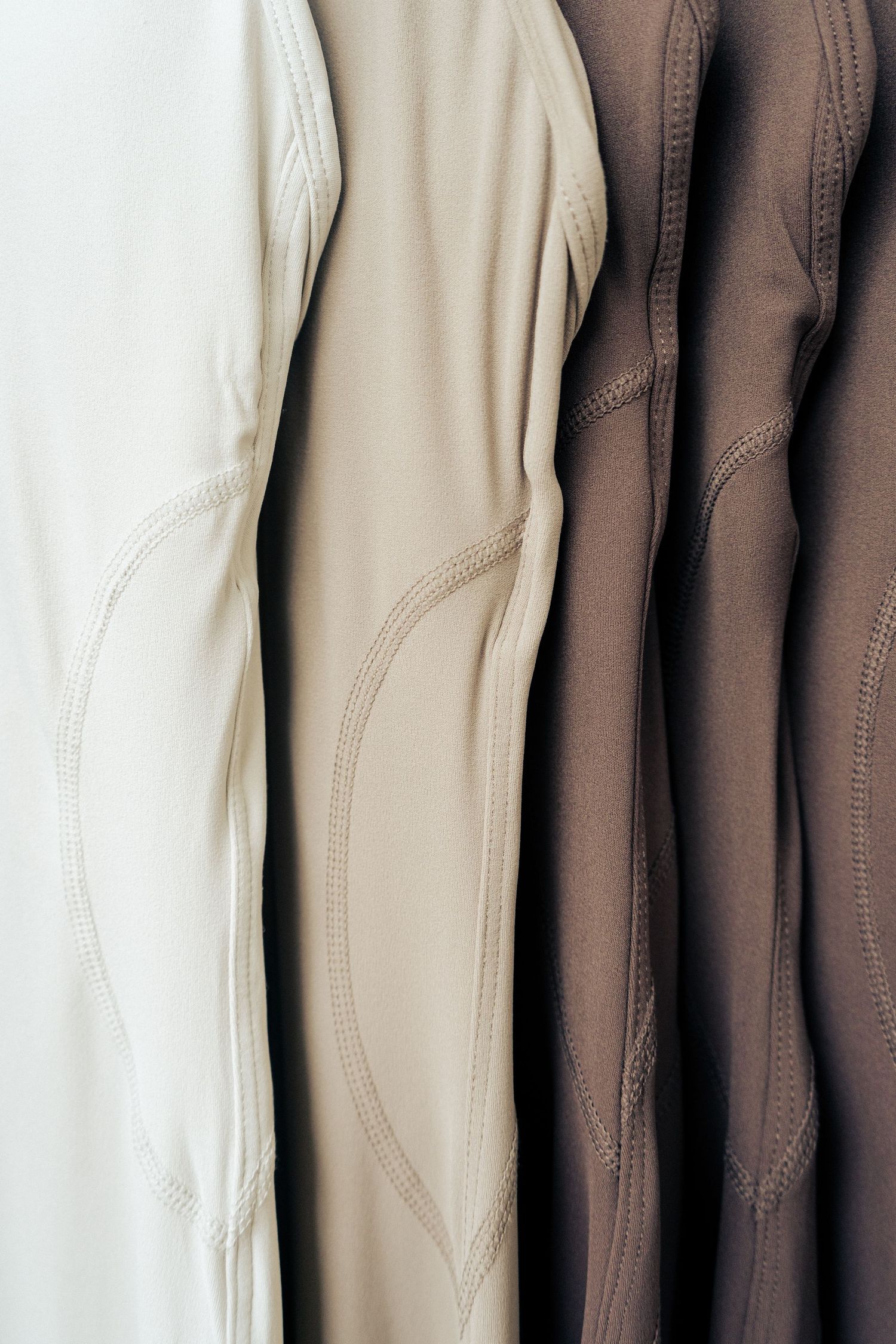 Detailed view of athletic leggings in cream, beige and brown tones showing seam design.