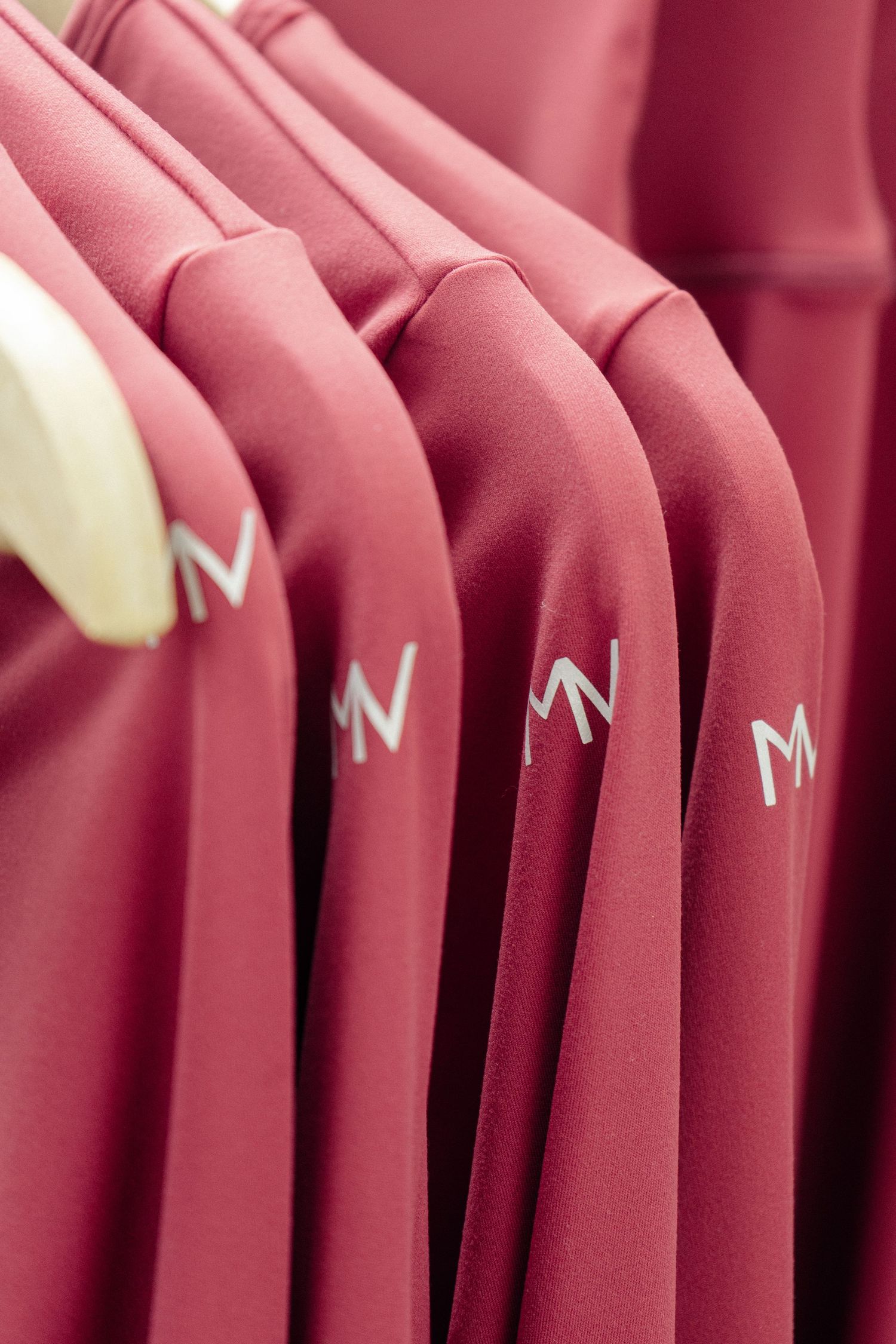 Close-up of pink athletic wear garments with M logo on hangers.