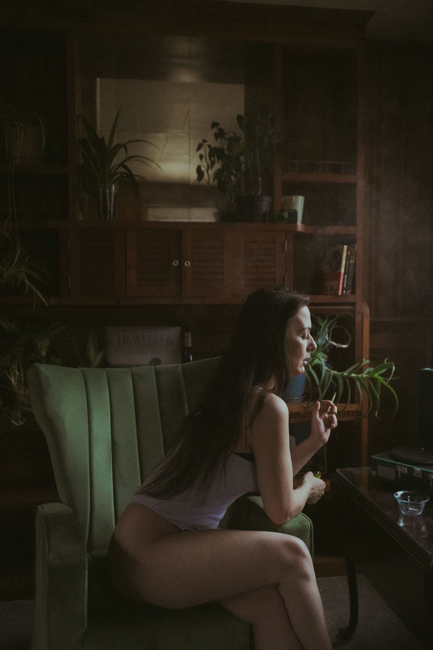 Moody indoor portrait with person relaxing in armchair near vintage furniture.