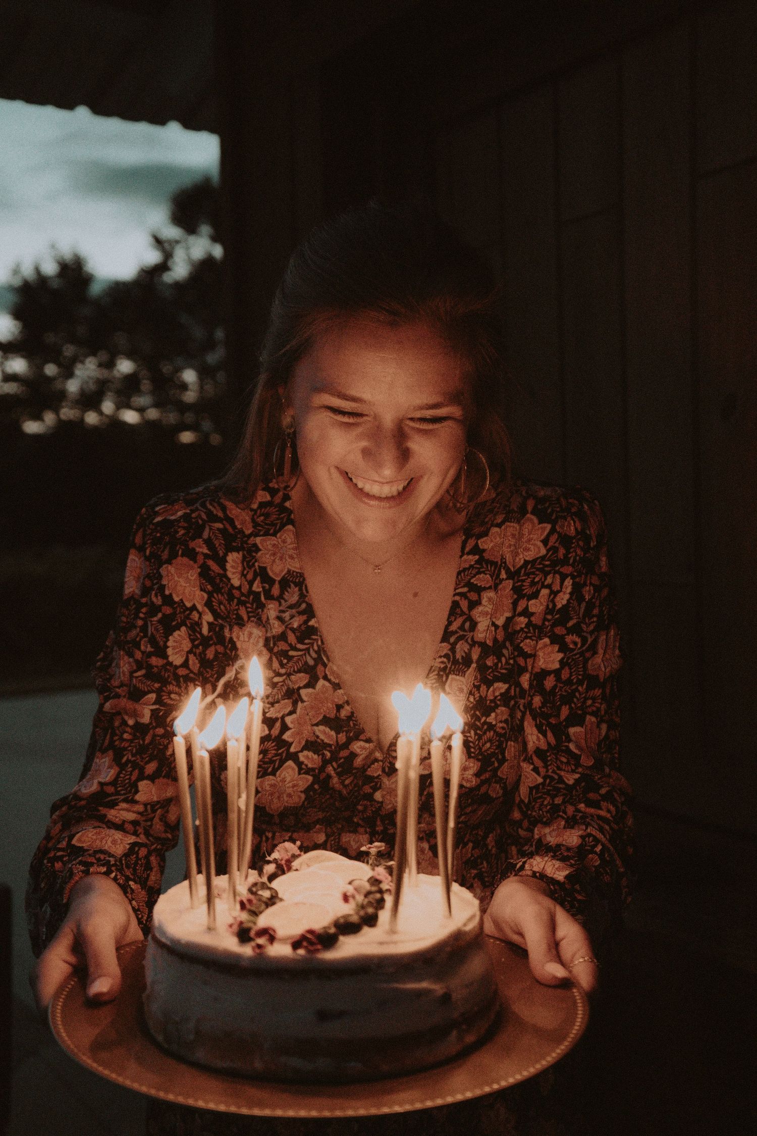 A birthday celebration with lit candles on a cake during sunset.