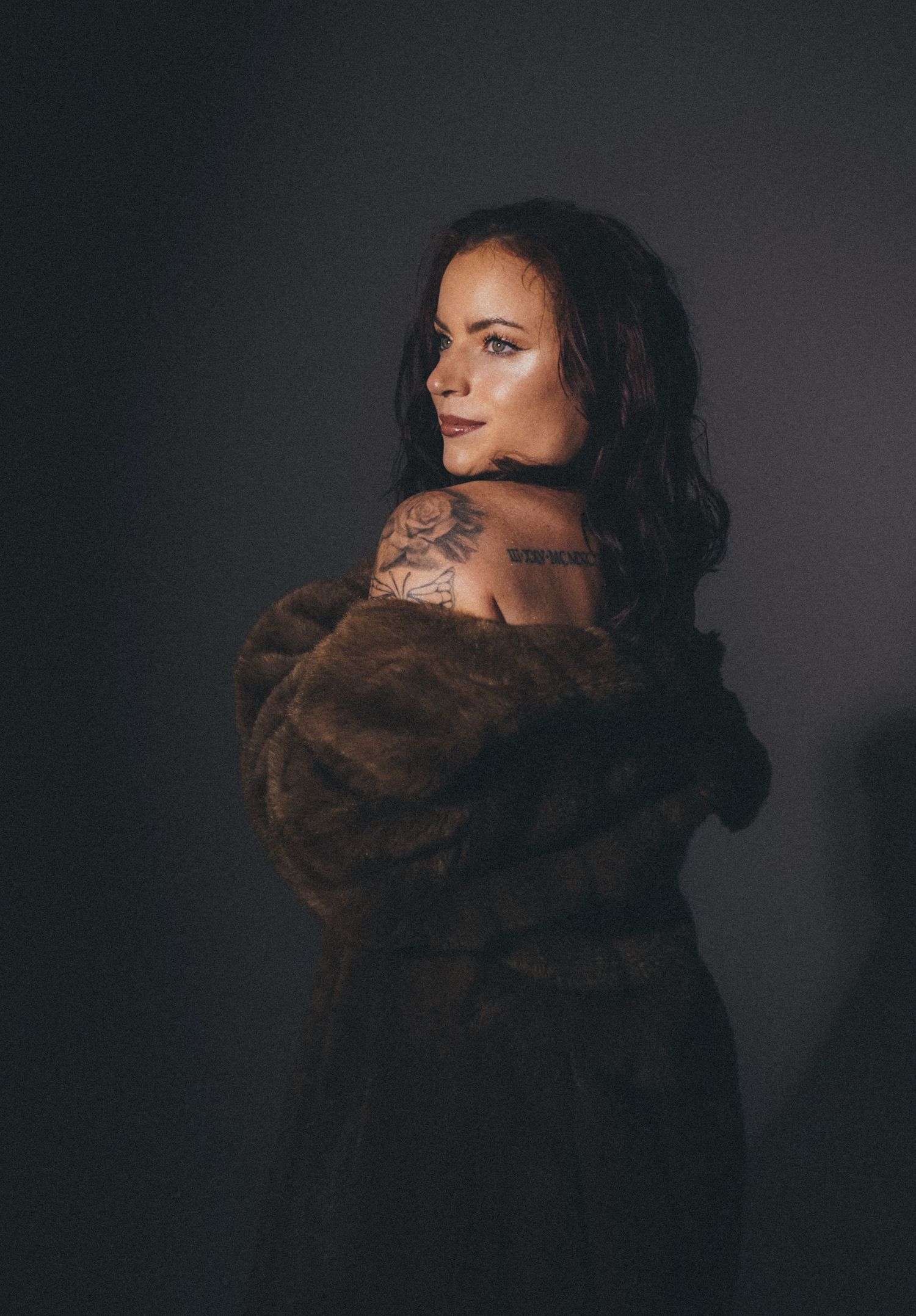 Moody portrait in brown fur coat against dark background.
