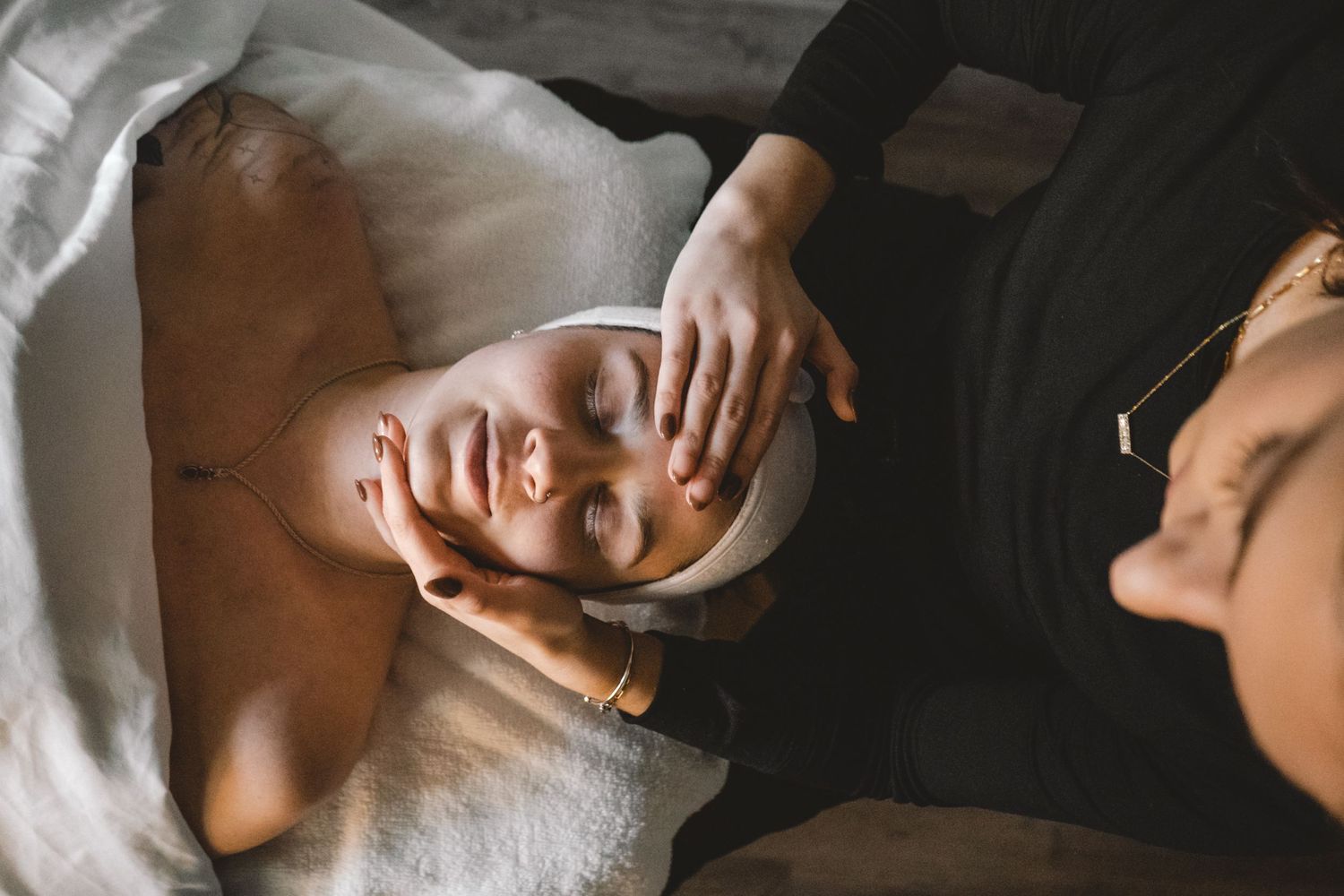 Hands performing facial massage treatment in spa setting.