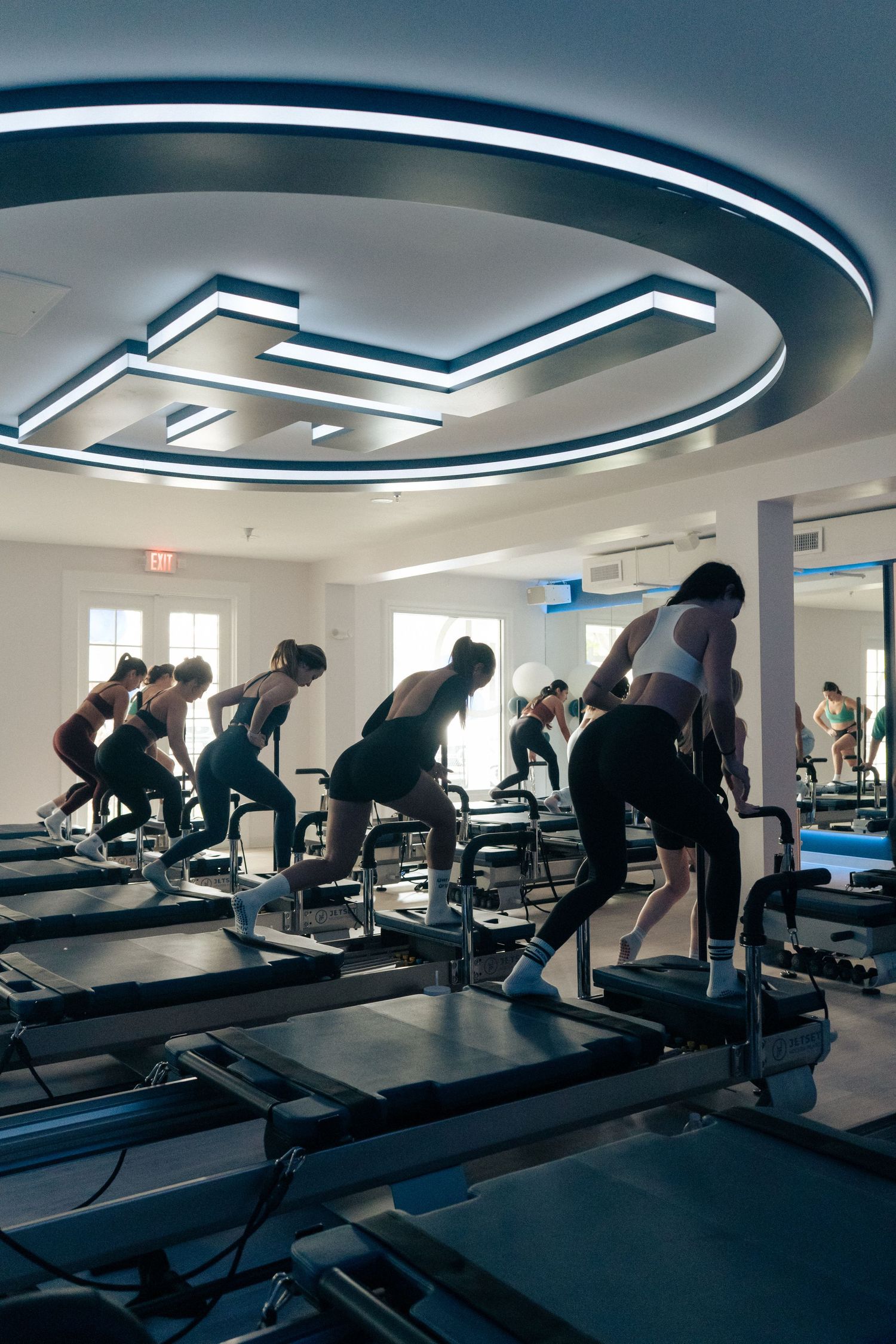 Overhead view of a fitness class working out on specialized equipment under modern lighting.