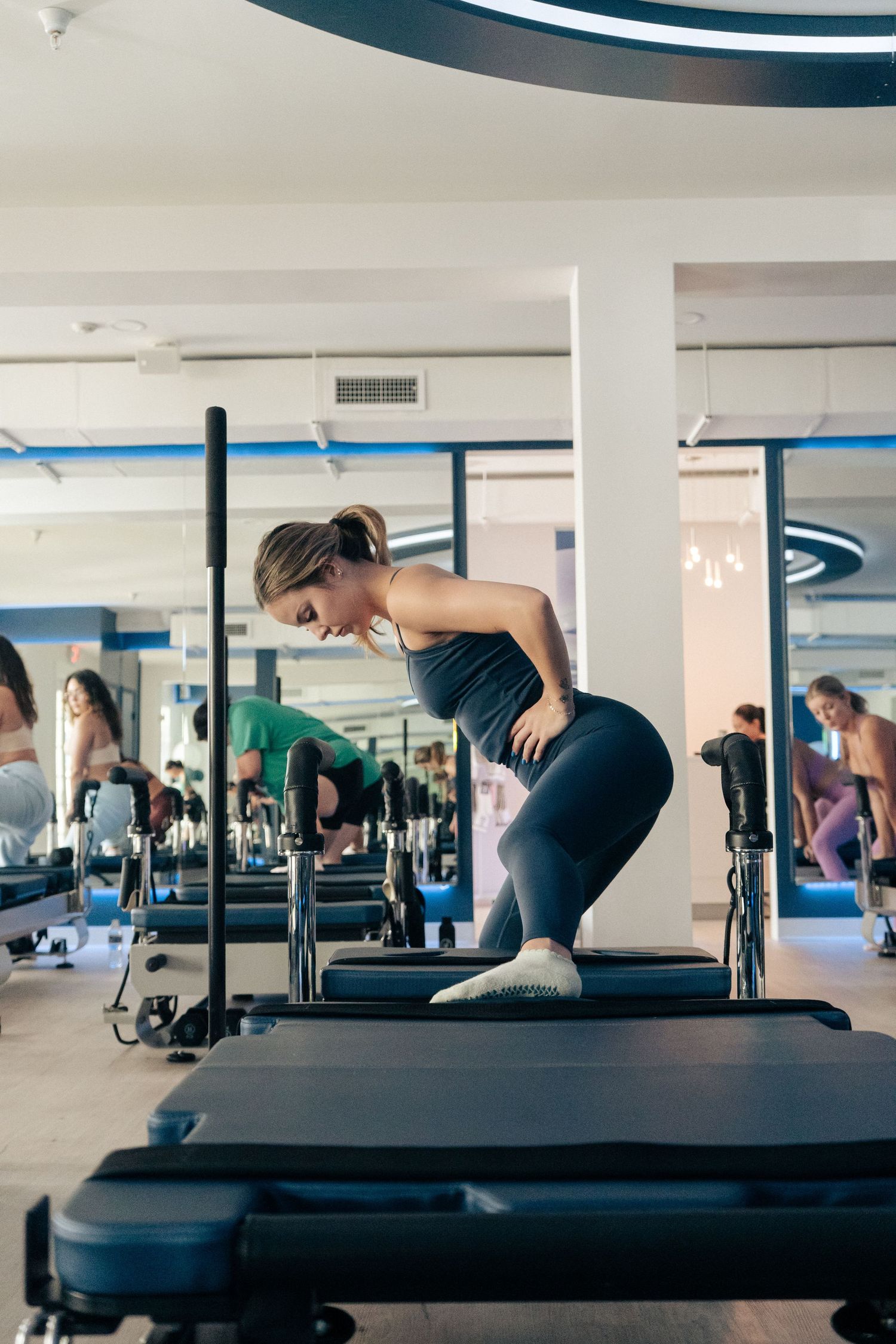Fitness participants engaging in pilates exercises on reformer equipment in a modern studio.