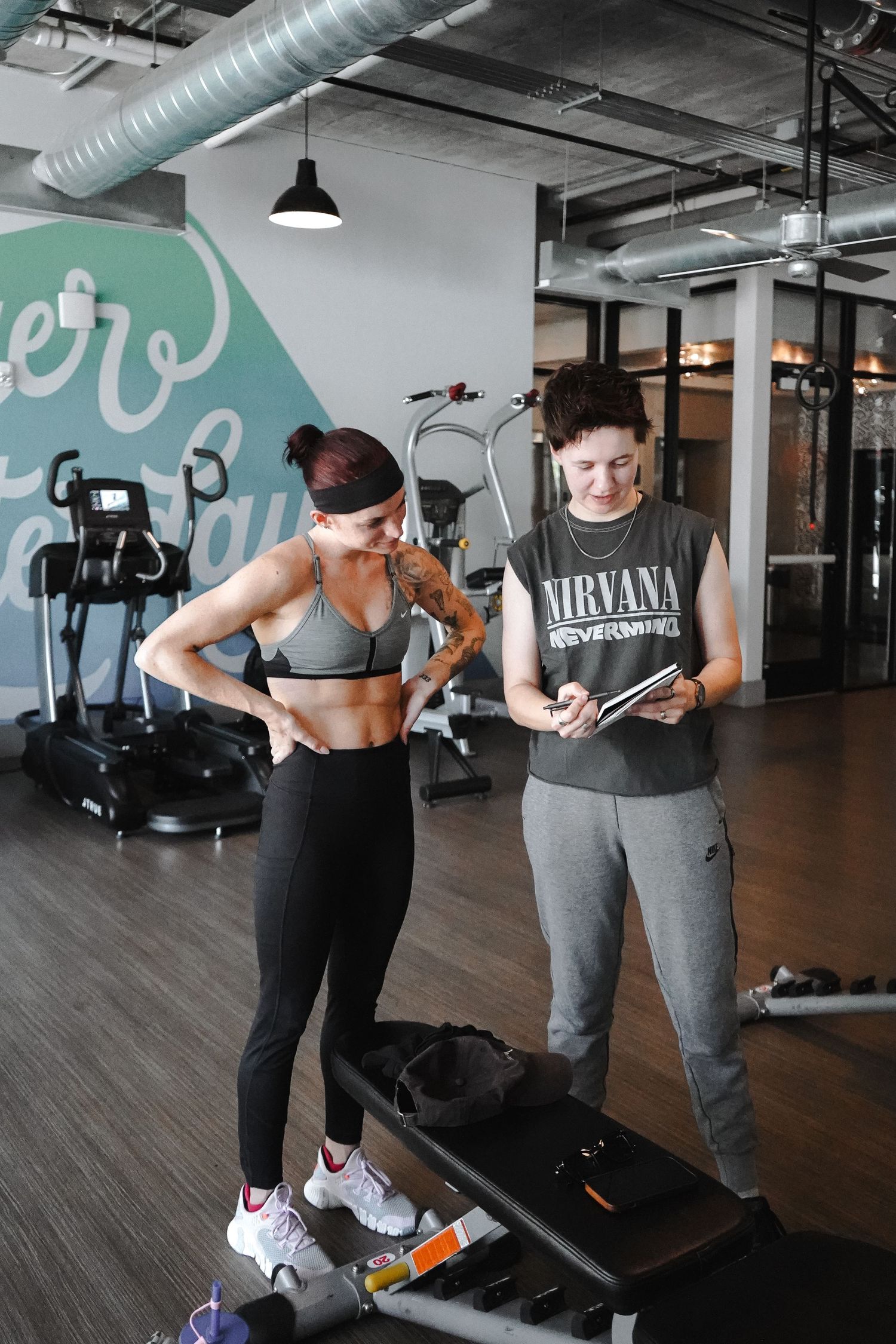 Fitness trainer and client reviewing workout plan in modern gym.