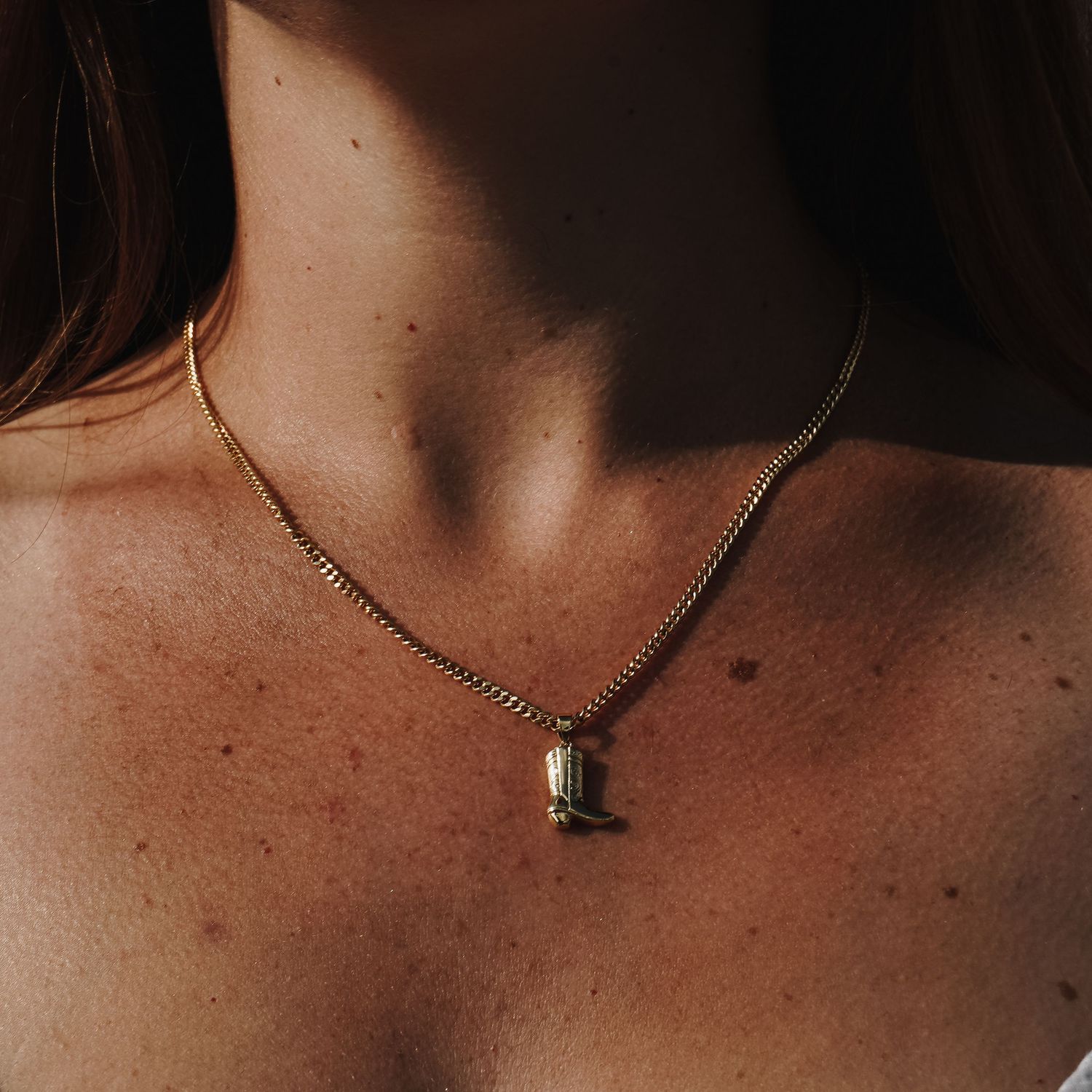 Minimalist gold necklace with single pendant captured in warm lighting.