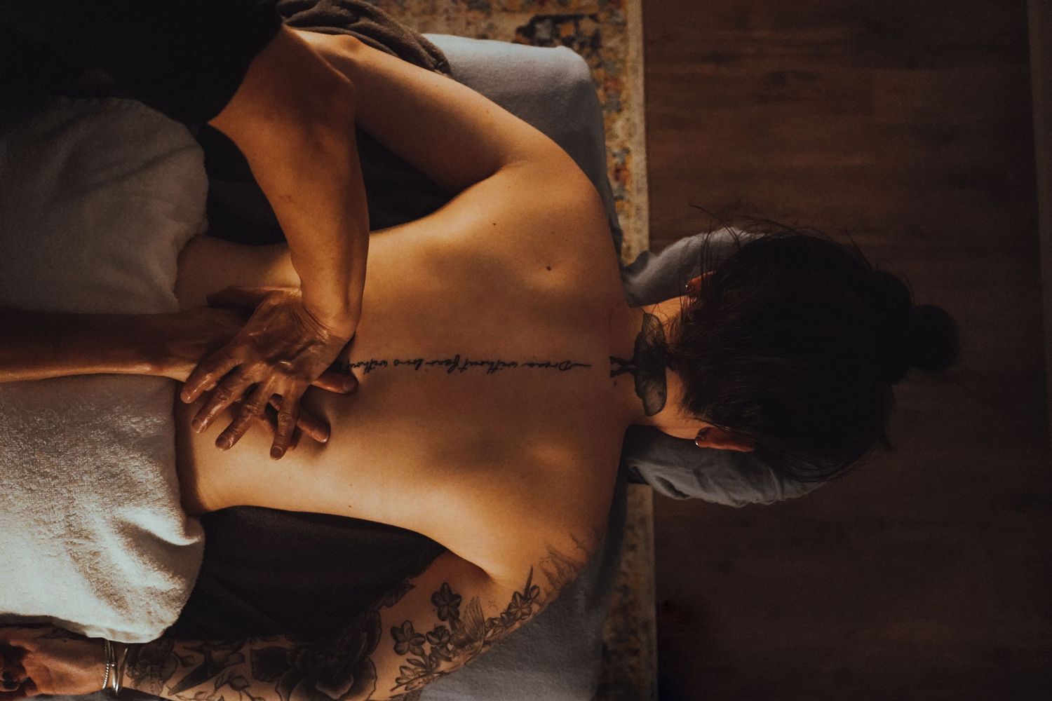 Person receiving a relaxing massage therapy treatment on a wooden table.