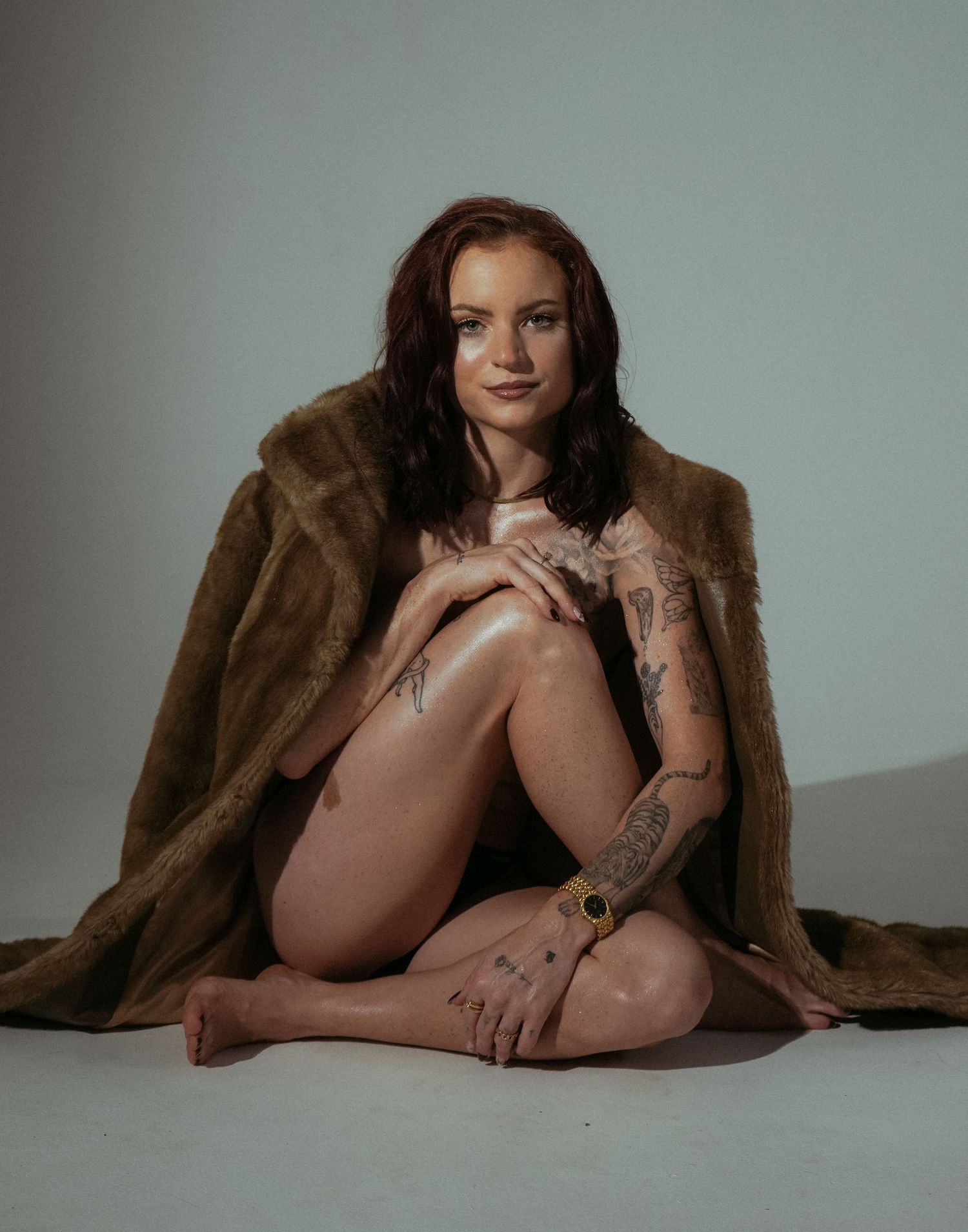 Artistic studio portrait with brown fur coat on light background.