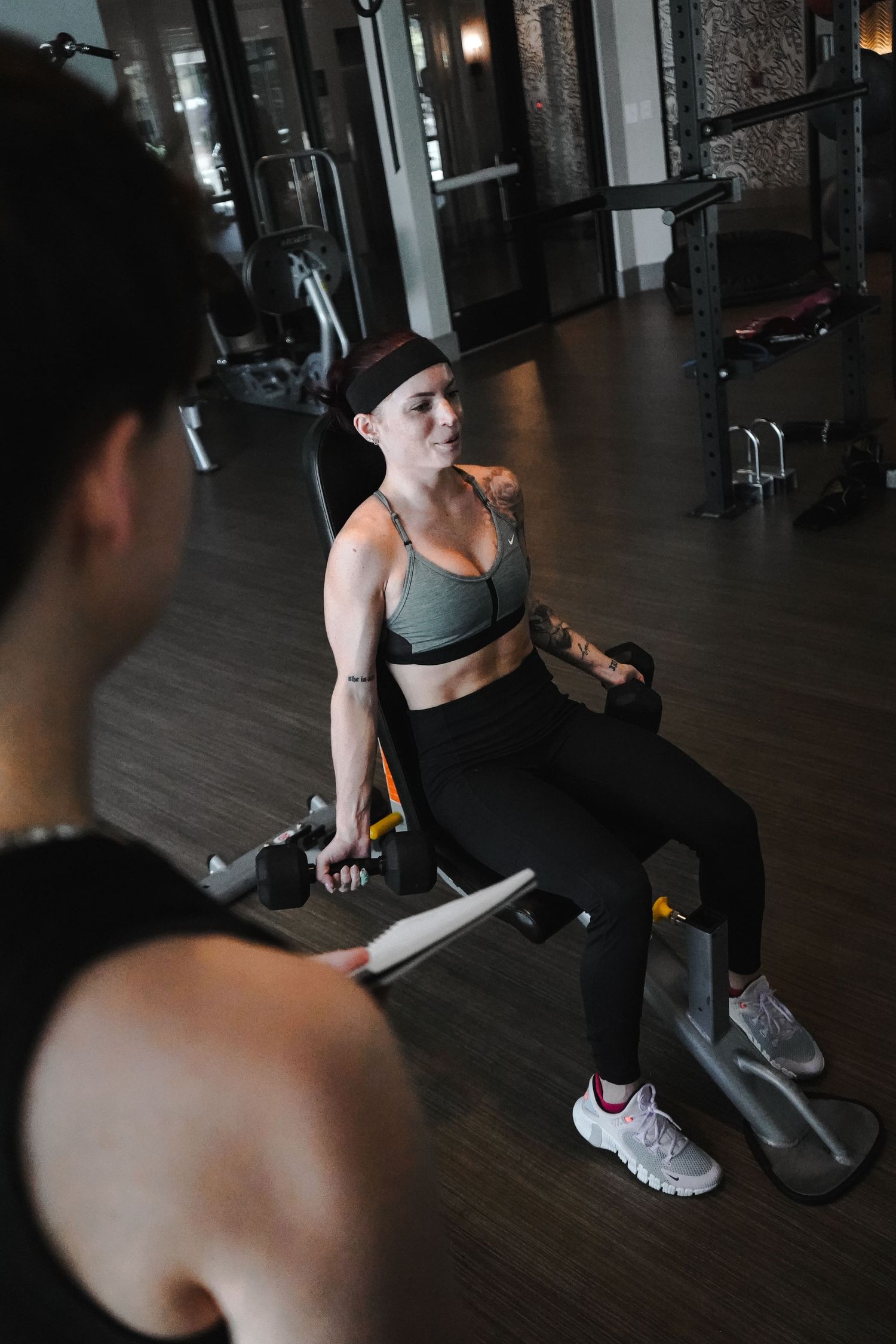 Person exercising on weight machine in dimly lit gym setting.