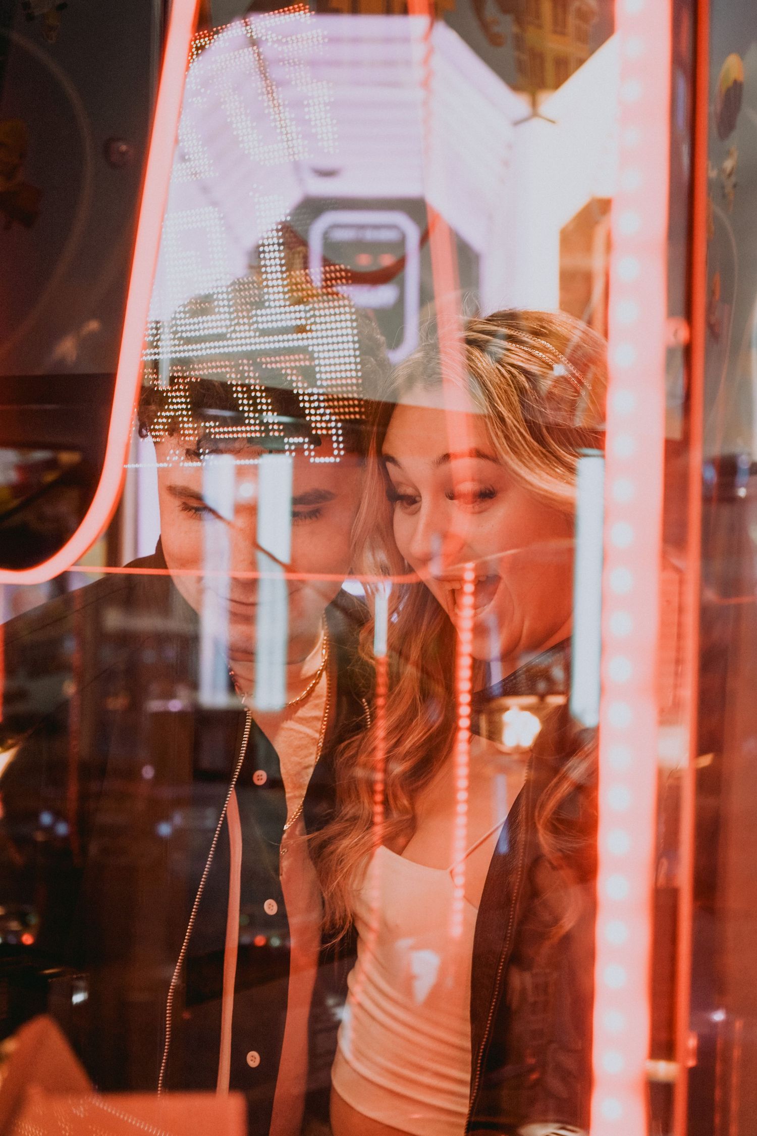 Reflection through red-tinted glass shows people looking through window display.