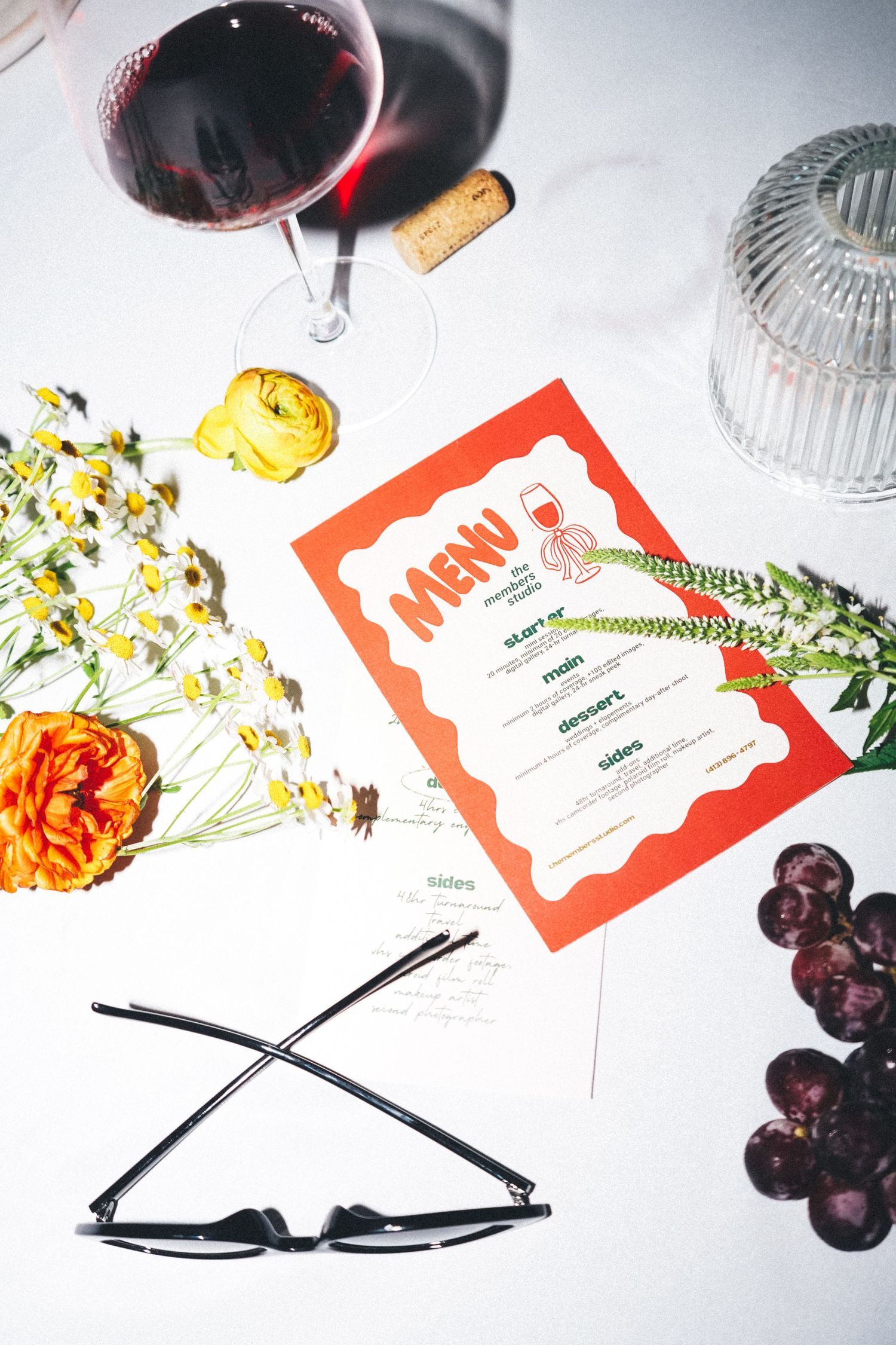 Table setting with wine glass, menu, flowers and grapes in an elegant arrangement.