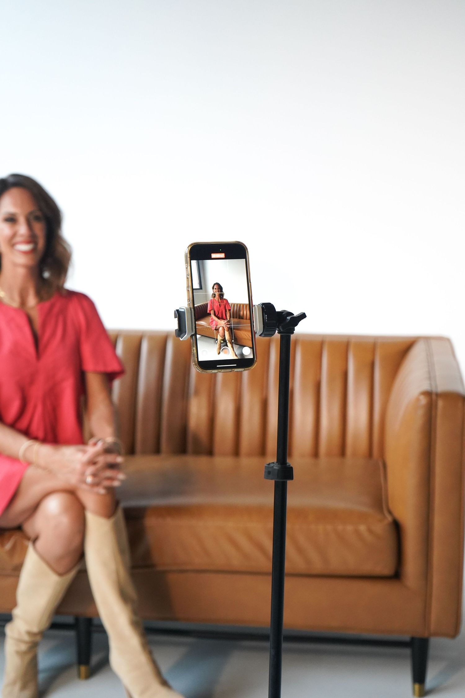 Phone mounted on tripod recording content in modern living room setting.
