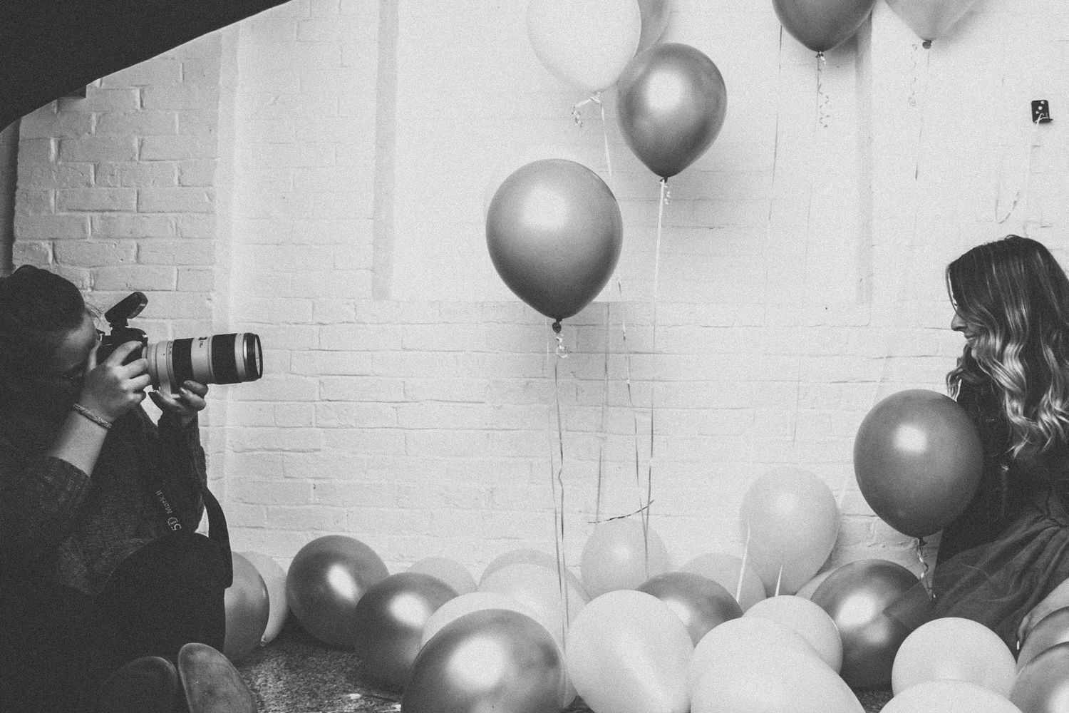 Black and white photo of a photoshoot scene with balloons and photographer silhouette.