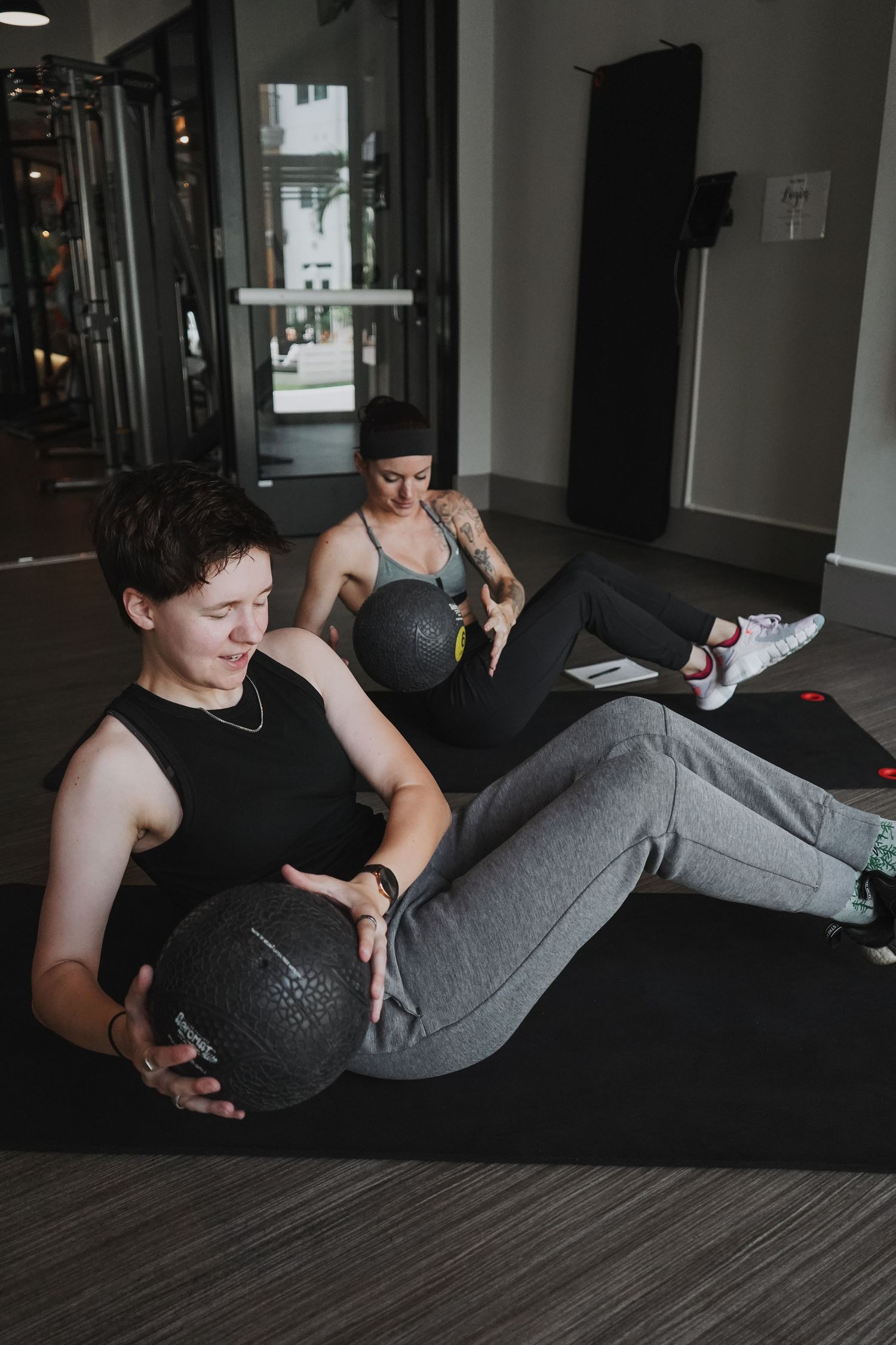 Person performing core exercises with medicine ball on gym floor mat.