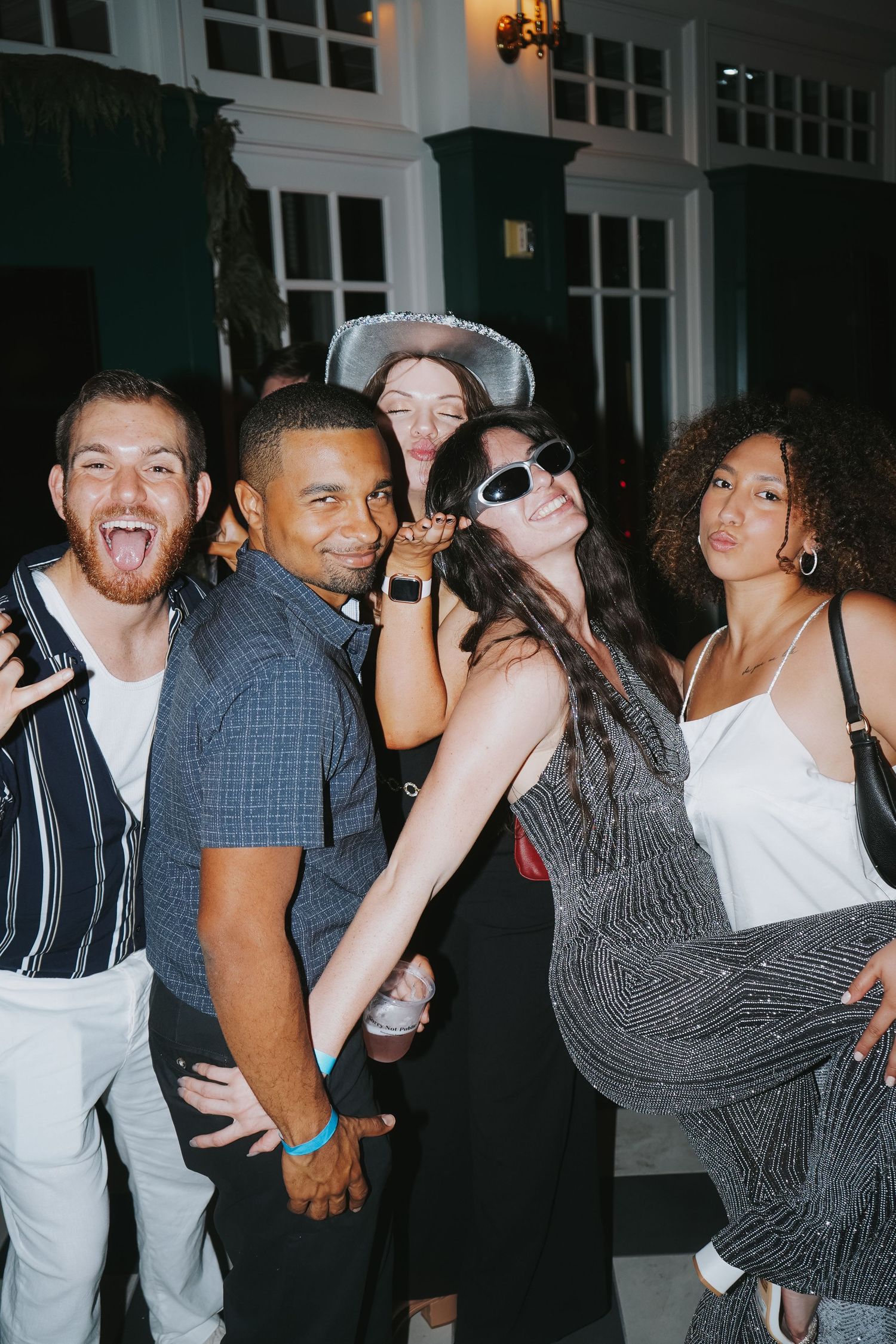 Group of friends striking playful poses at a nighttime party.