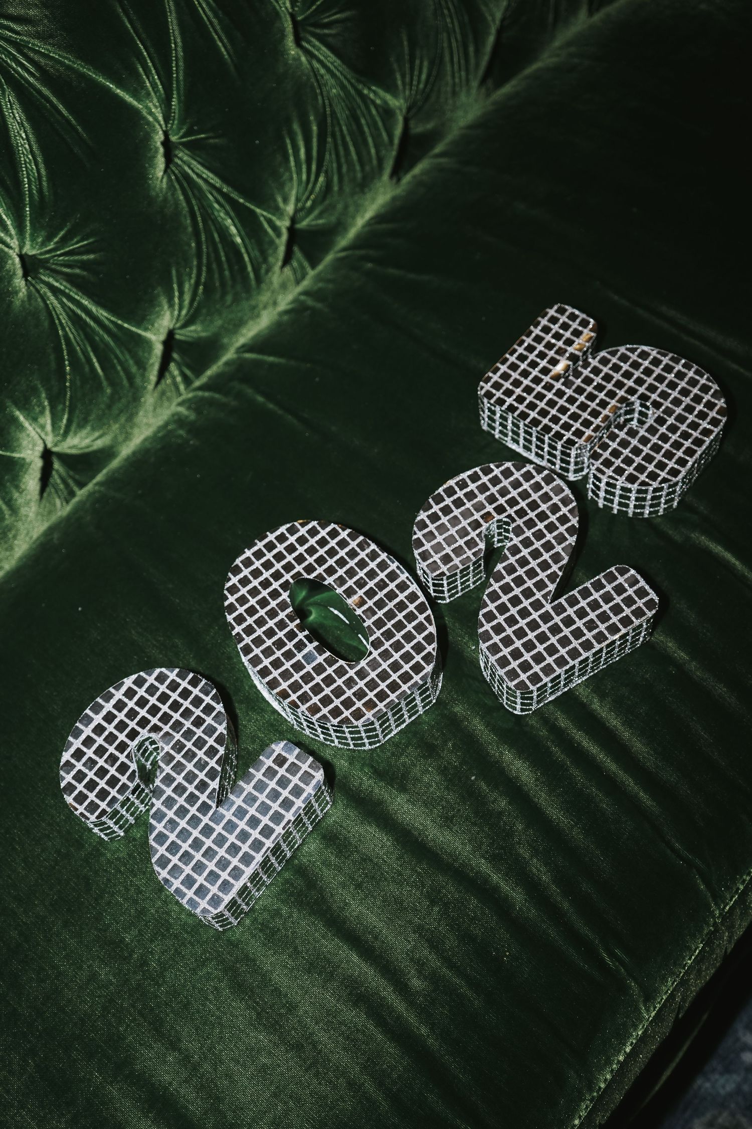 The year '2022' in metallic mesh numbers displayed on dark green velvet.