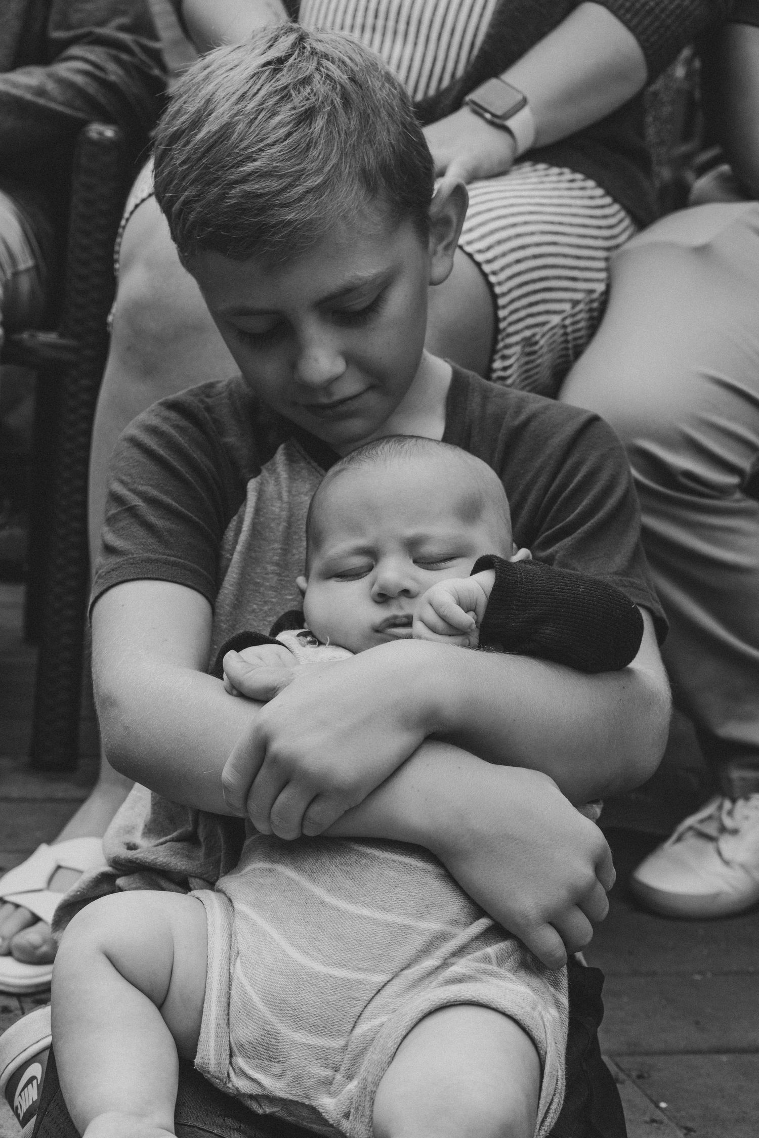 Tender black and white moment showing someone holding a sleeping baby.