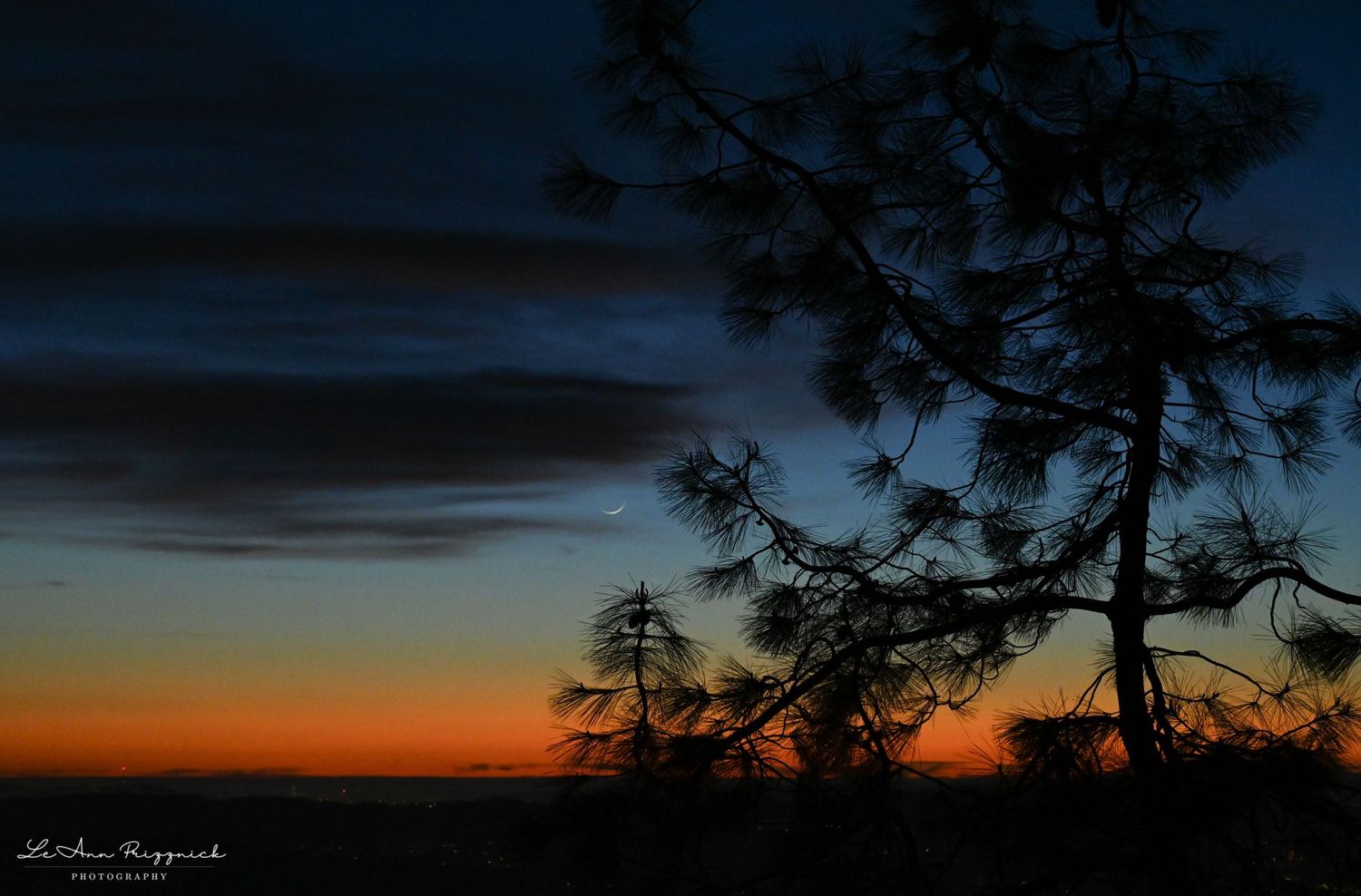 A sliver moon with a gorgeous post-sunset rainbow of colors.