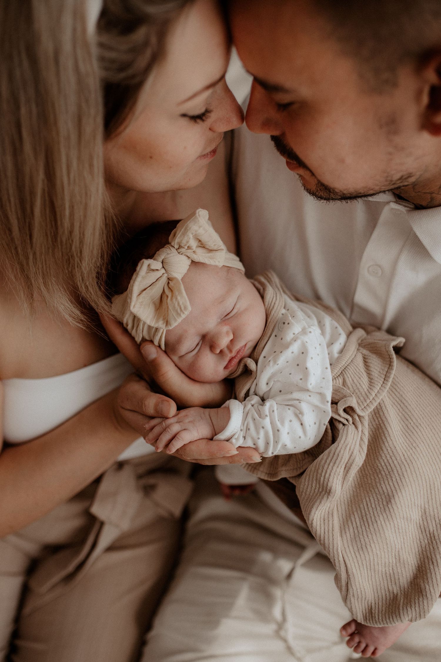 Mama, Papa und Neugeborenes kuscheln im Tageslichtatelier in Franken – warme, entspannte Atmosphäre, natürliche und zeitlose Familienfotos